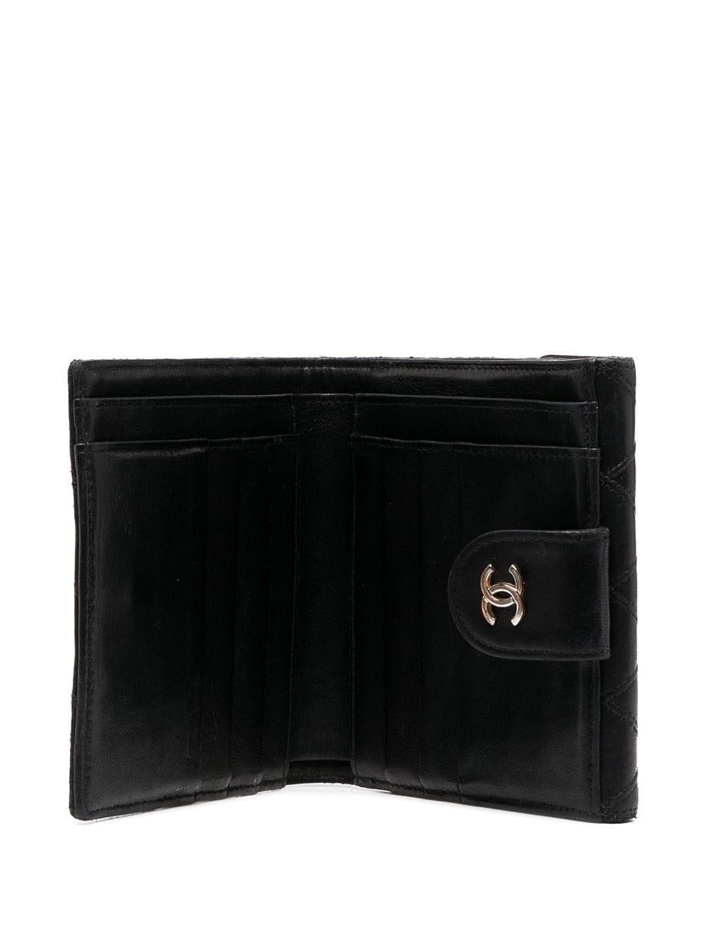 Chanel black quilted lamb wallet featuring signature interlocking CC logo,  multiple internal slip pockets, internal card slots, front flap pocket, leather lining.
Length 3.9in (10cm)
Width 4.3in. (11cm)
Depth 0.8in. (2cm) 
In good vintage