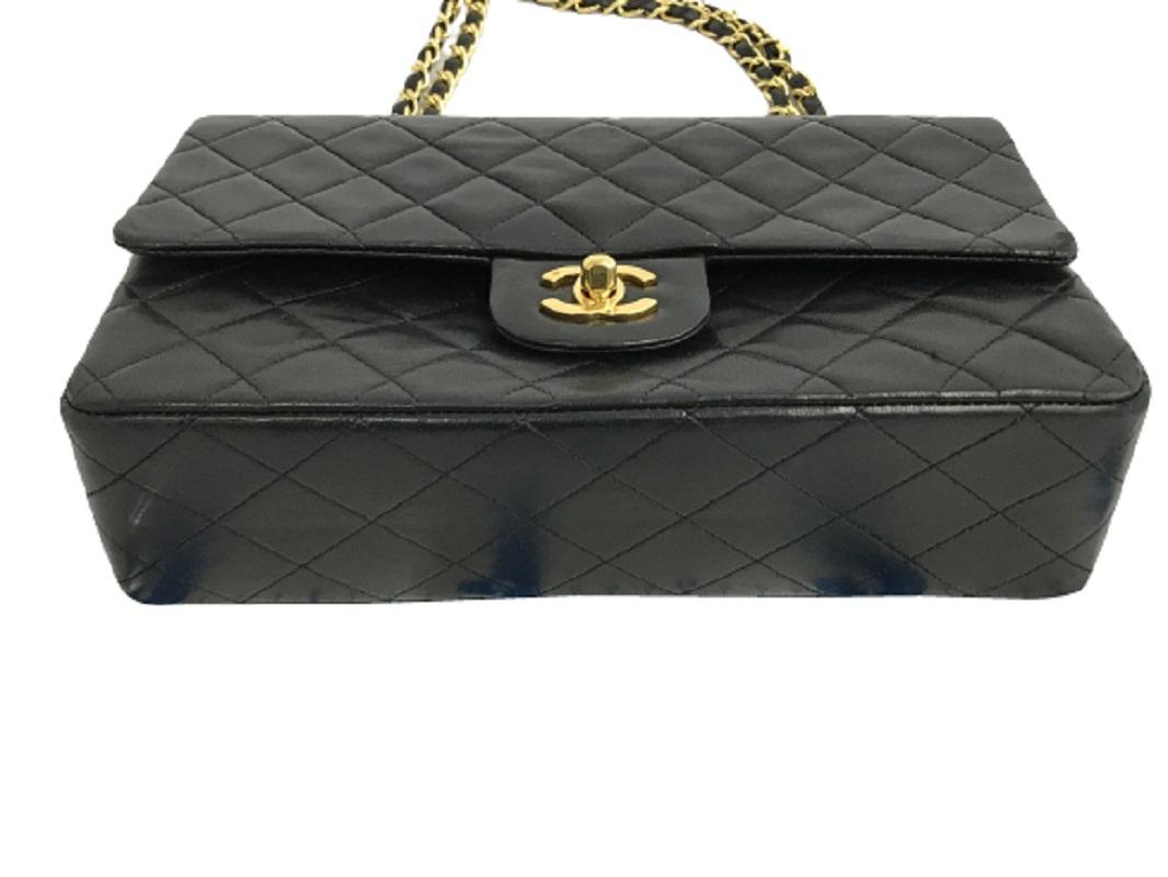 Chanel Flap bag is crafted of soft black diamond-quilted Lambskin leather and features a prominent gold-tone hardware, an interlocking CC turn-lock closure at the front, a long woven leather and gold-tone chain shoulder strap and a patch pocket at
