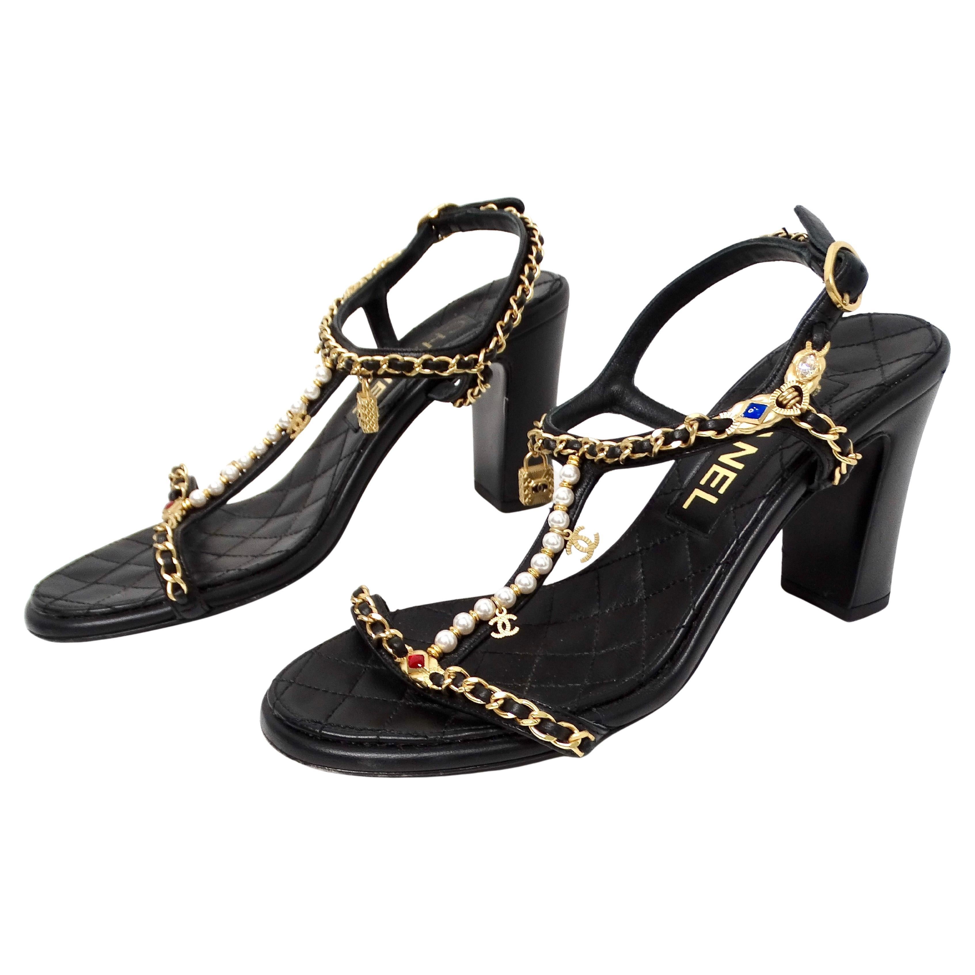 Les sandales à breloques en chaîne en cuir d'agneau matelassé noir de Chanel, signées 2022, incarnent le luxe et l'élégance sophistiquée. Confectionnées en cuir d'agneau matelassé, ces sandales témoignent du savoir-faire de Chanel et de son style