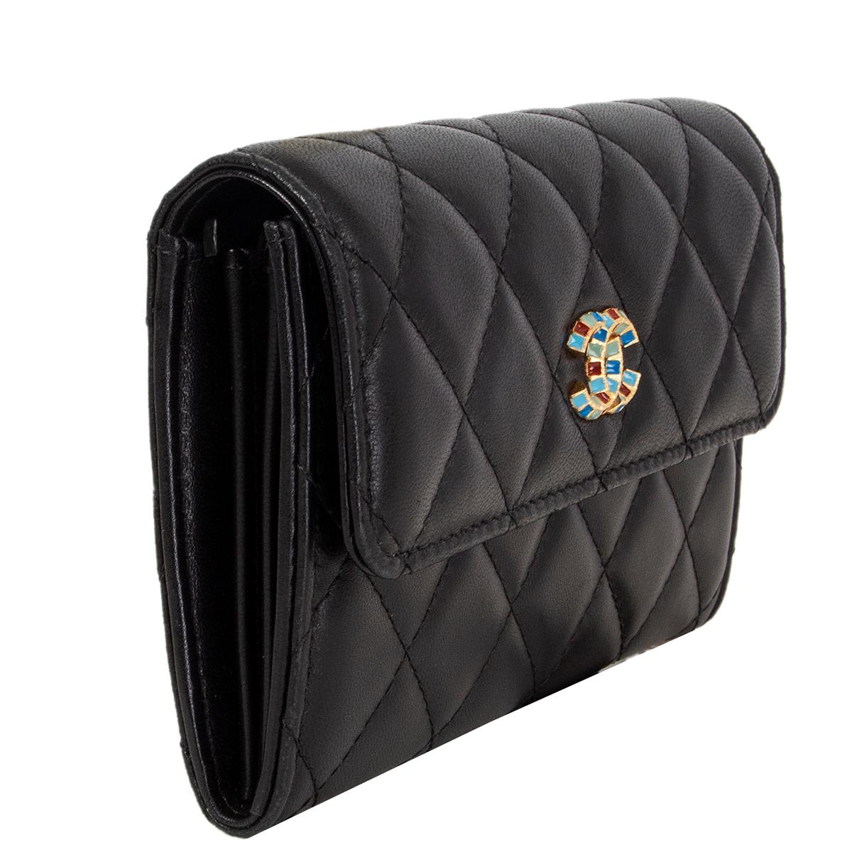 Chanel quilted wallet in black lambskin with multicolor 'CC' push button closure. Lined in black lambskin and nylon with a zipper coin pocket in the middle and three credit card slots against the front and back. Slit pocket against the back. Has