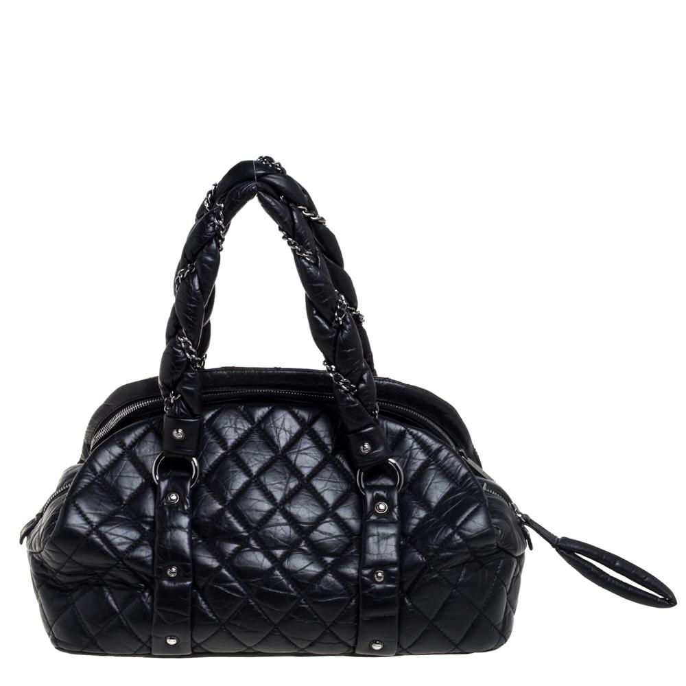 This exquisitely designed bowler bag from the house of Chanel has been crafted from black leather in a quilted design. The braided handles are accentuated with chain links, and the exterior features silver-tone hardware, including the iconic CC