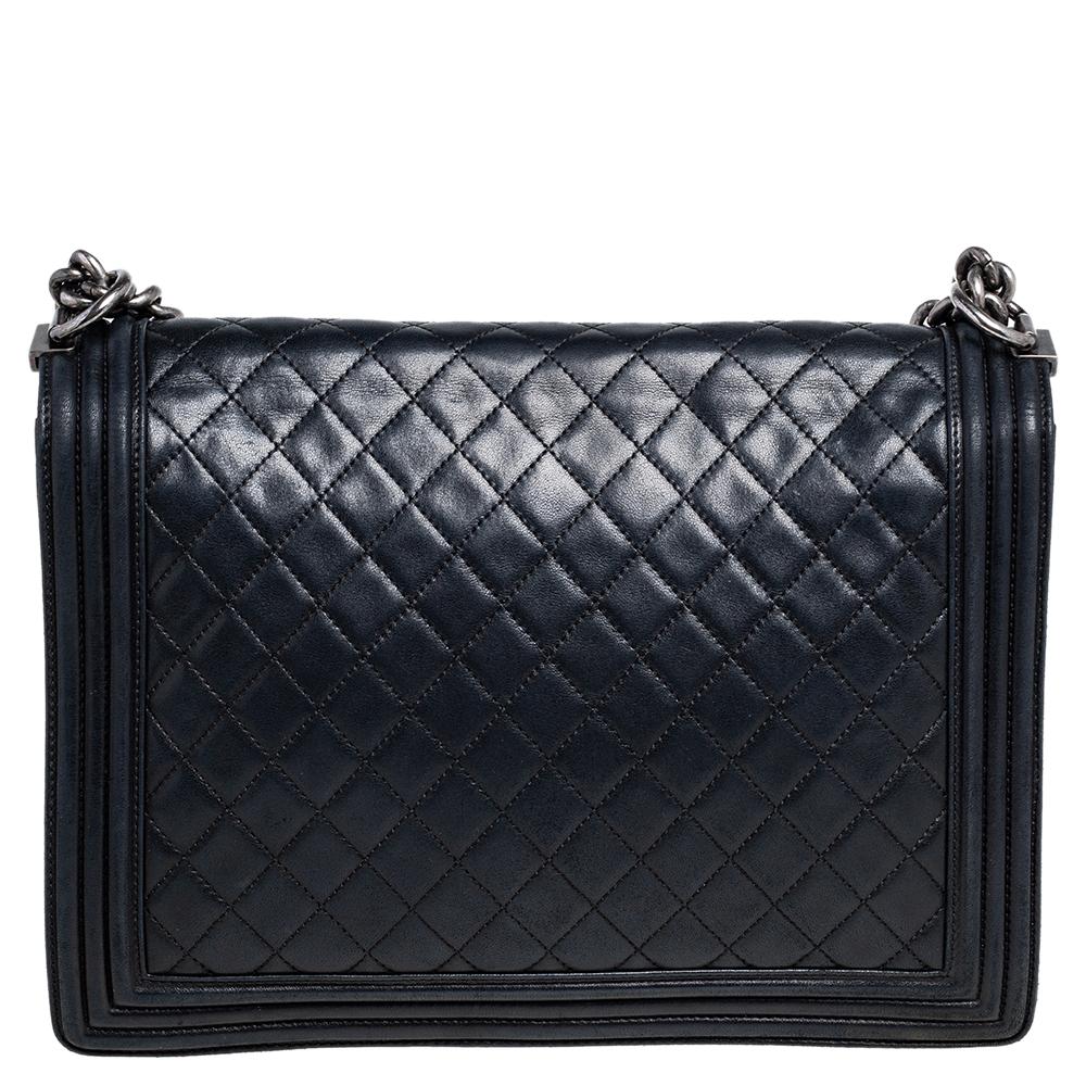 The Boy flap bag is an icon of Chanel's. This here is a version in black quilted leather. It brings the signature label within the fabric interior and the iconic CC push lock on the flap. The piece has silver-tone hardware and a shoulder chain link