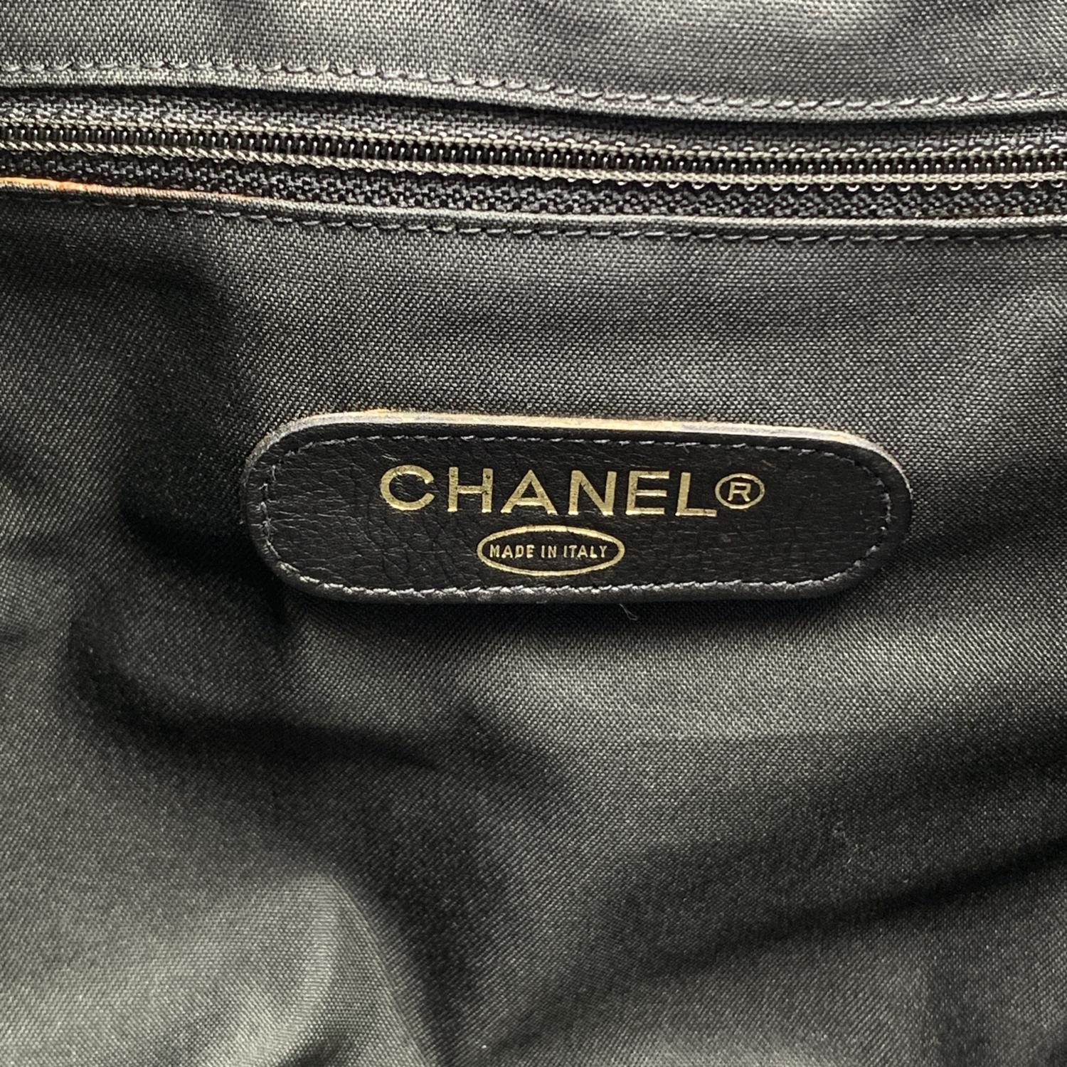 Chanel travel duffle bag in black leather with quilted stitching. It features upper zipper closure, double handle, adjustable shoulder strap and name tag with CC logos. Black canvas lining and 2 side zip pockets inside. 'CHANEL - Made in Italy' tag