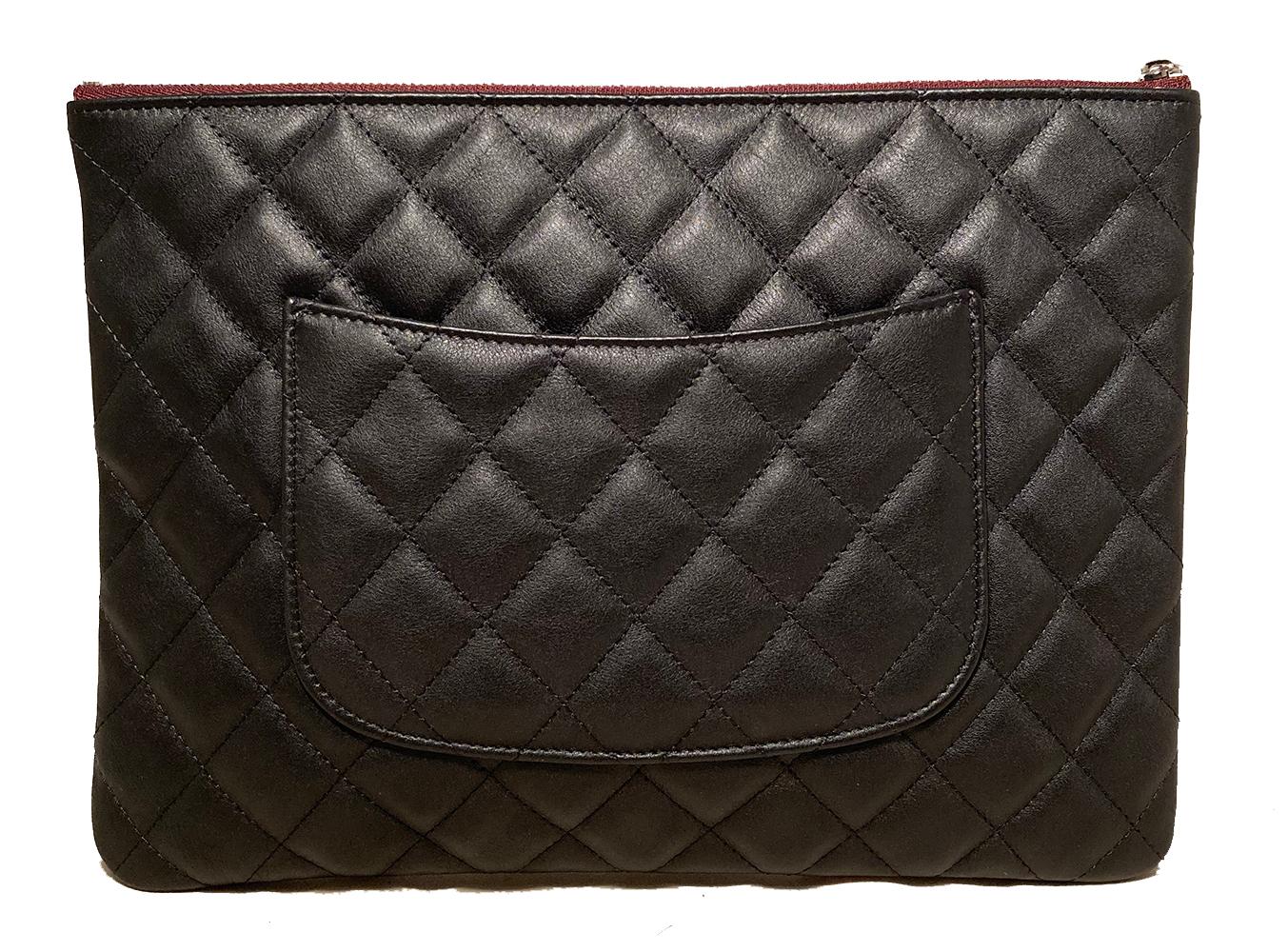 Chanel Black Quilted Leather Medium O Pouch in Like New unused condition. Black diamond quilted calfskin leather exterior with tiny silver CC logo emblem along front and back side slit pocket. Top Maroon leather zip pull opens to a maroon nylon