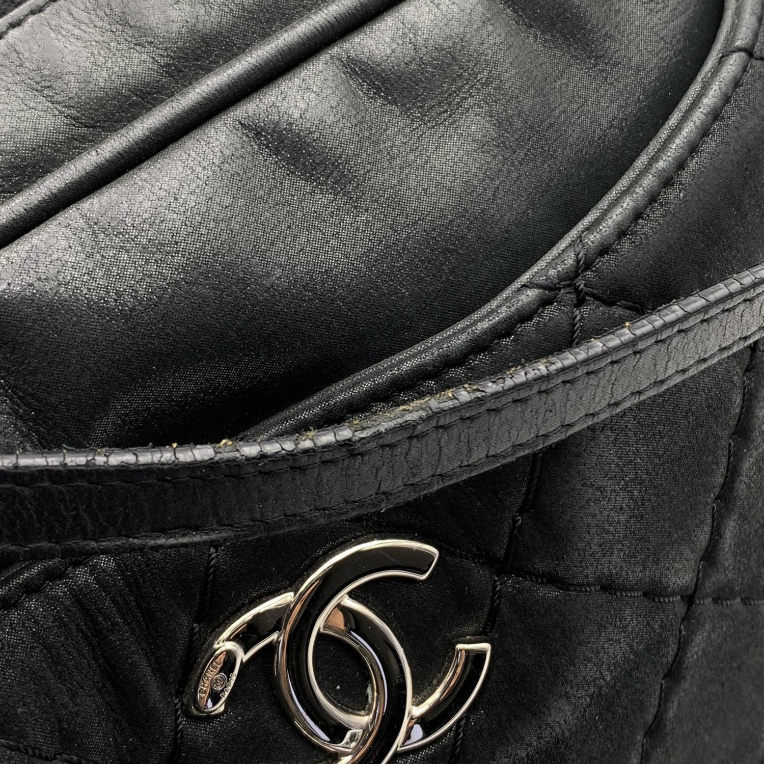 Chanel Relax CC Tote Camera Shoulder Bag crafted in black quilted shimmery leather. Silver metal CC -. Chanel logo. Upper zipper closure. Front and rear pockets with magnetic button closure. Double leather handles and removable interwoven leather