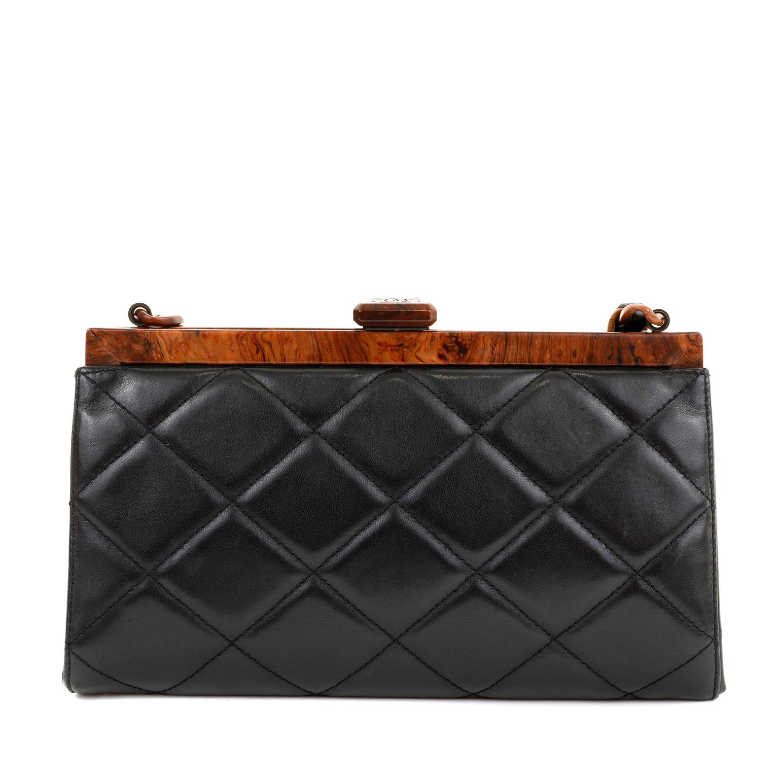 This authentic Chanel Black Quilted Leather Wood Framed Bag is in pristine condition.  Very rare design with resin accents that mimic natural wood elements.  Black quilted leather with framed top and push lock closure. Single leather and “wood” link