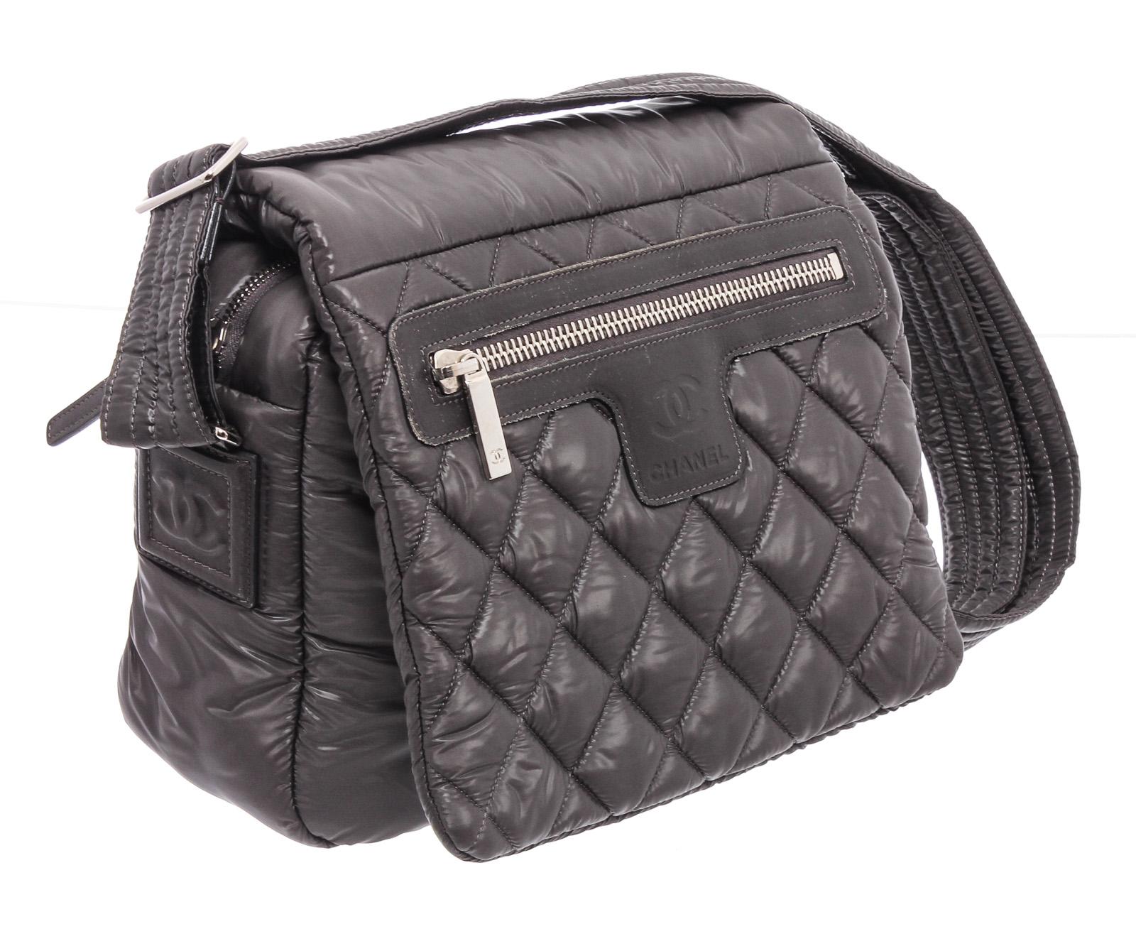 Black quilted nylon Chanel Coco Cocoon Messenger Bag with silver-tone hardware, tonal leather trim, single flat shoulder strap, single exterior zip pocket, embossed logo accent at front face, burgundy nylon lining, single interior zip pocket and zip