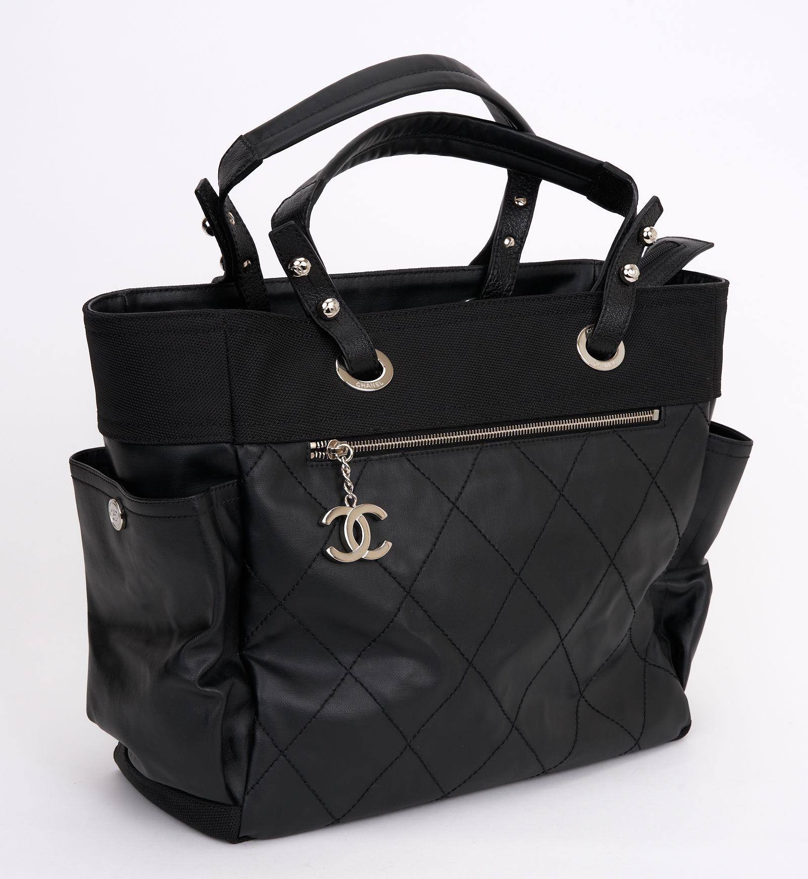 This is Chanel Coated Canvas Quilted Paris Biarritz Tote in black. This super chic tote features quilted coated canvas. The bag features tall top handles, side pockets, a front zipper pocket with a chanel CC zipper pull, and silver hardware. The top