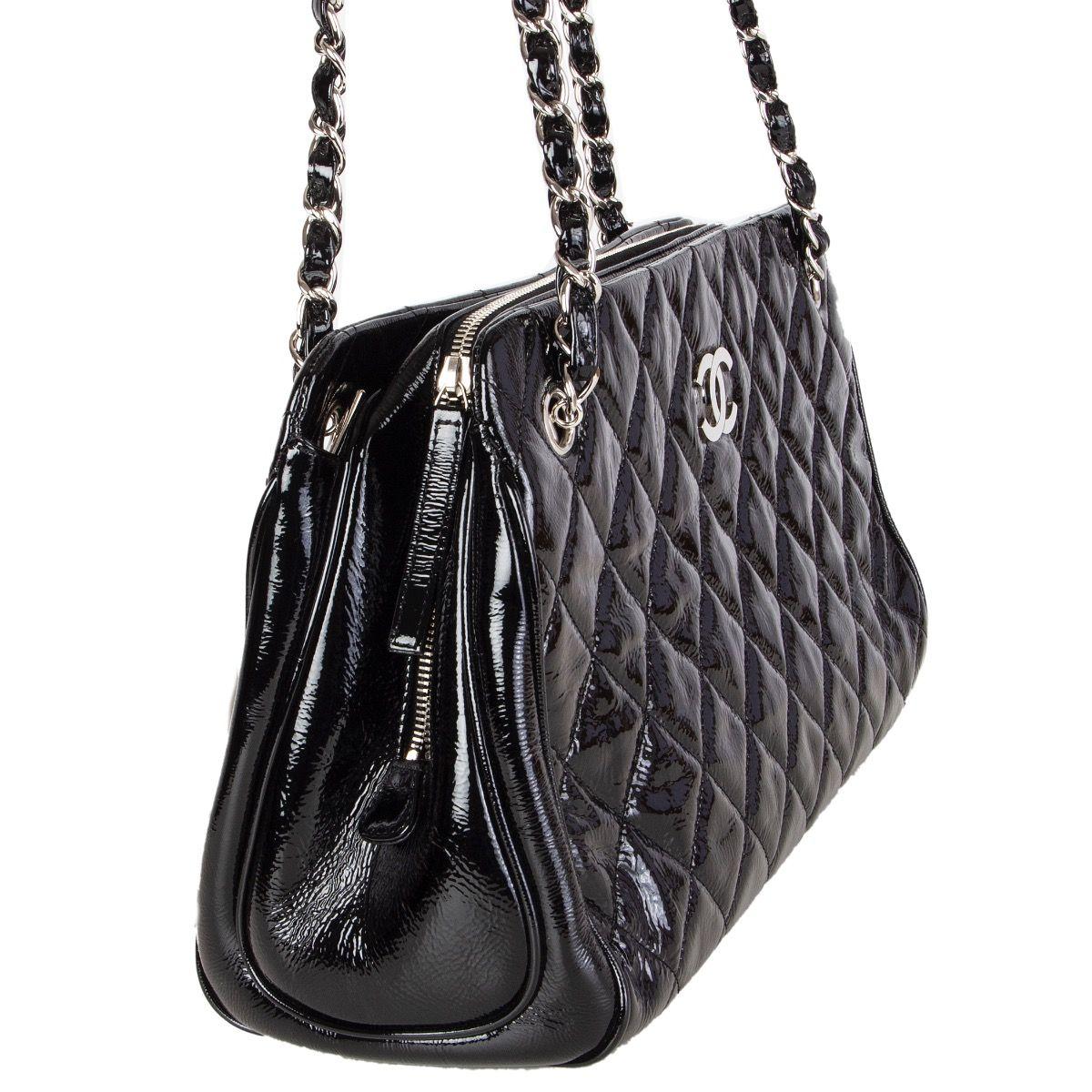 Chanel shoulder bag in black quilted patent leather with silver-tone CC and chain. Open pocket on the outside back. Two open pocket on each side with a zipper pocket in the middle. Lined in black leather with two open pockets against the front and a