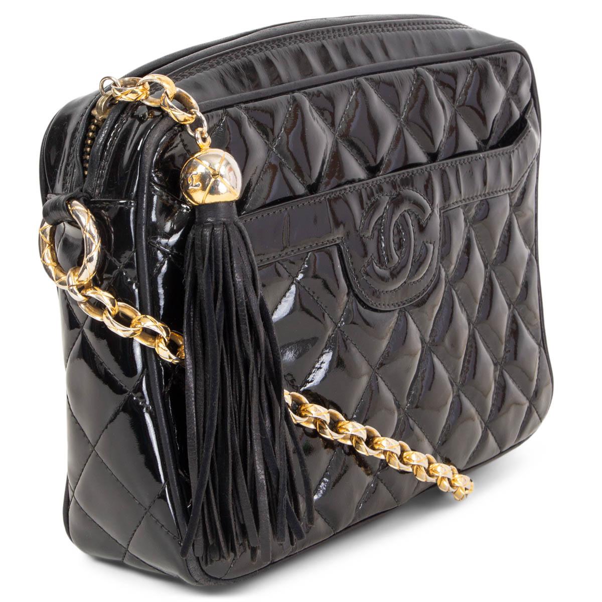 100% authentic Chanel tassel camera shoulder bag in black patent leather with gold-tone chain strap and a front pocket with CC logo stitching. Opens with a tassel zipper on top and is lined in black smooth lambskin with one zipper pocket against the