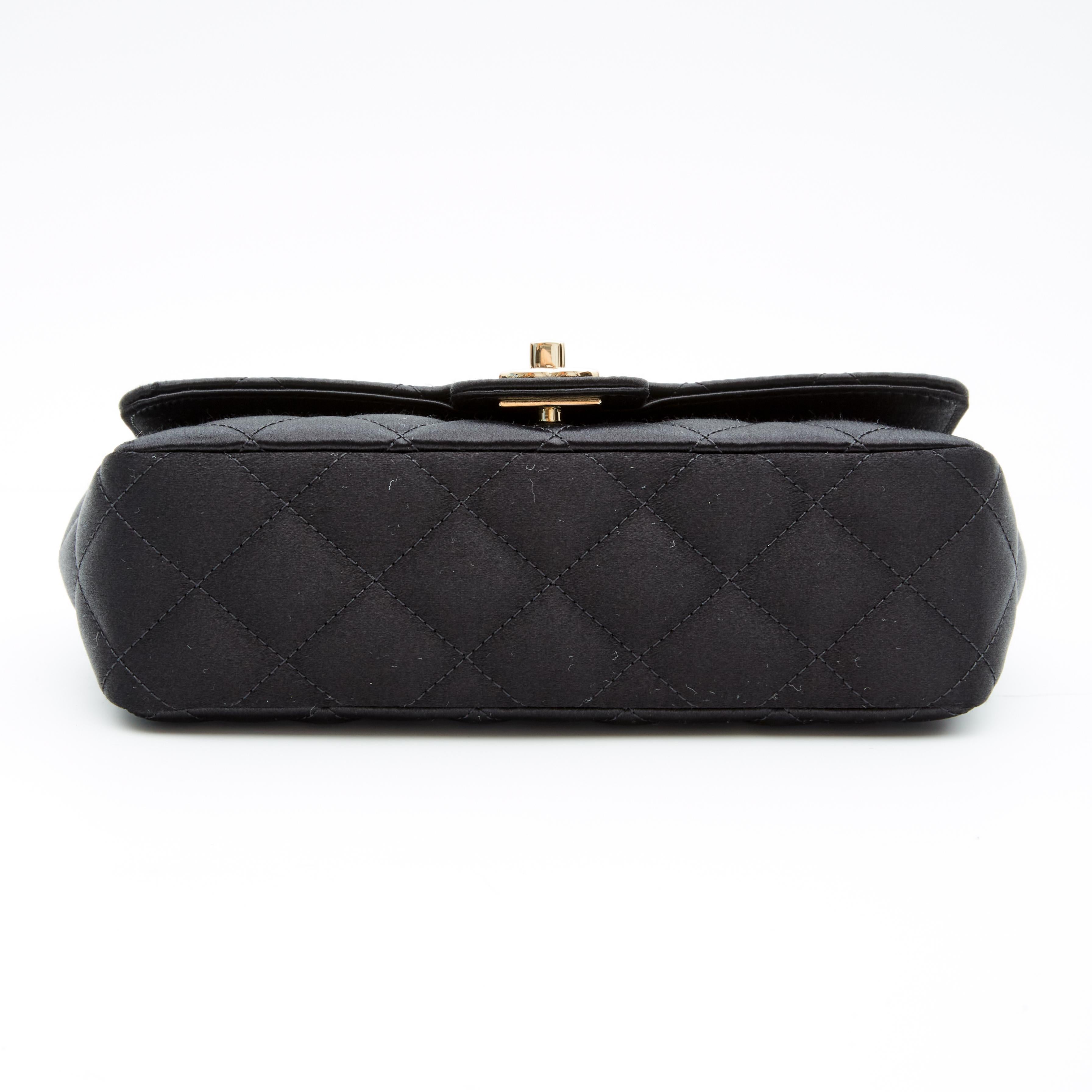 This Chanel Black Quilted Satin Camellia Mini Flap Bag is a rare and beautiful. The bag features diamond stitched quilted satin, gold-tone hardware, a front flap with the signature interlocking CC turn lock closure, and a gold-tone chain interlaced
