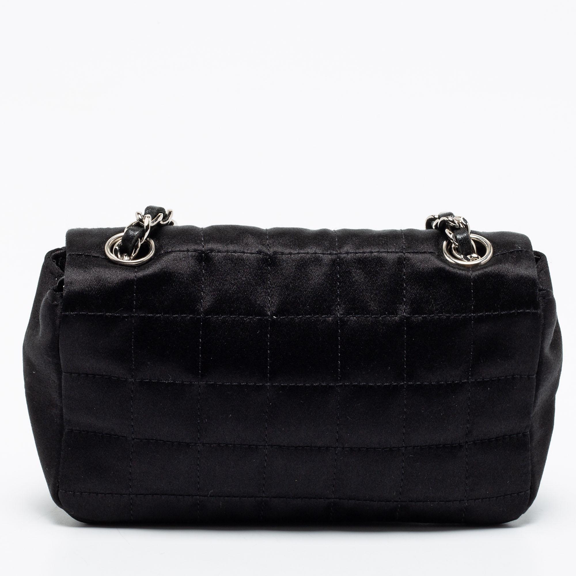 Made with the utmost skill, this black Chanel flap bag is an immaculate balance of sophistication and brilliant craftsmanship. The satin creation is detailed with the chocolate bar quilt, mirror & lipstick motifs, and the CC turn-lock on the flap.