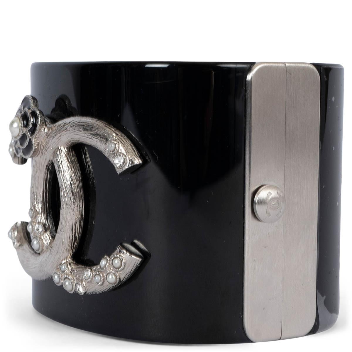 100% authentische Chanel 2014 Kamelie Manschette in schwarz glänzendem Harz mit CC-Logo mit faux Mini-Perlen verziert. Brandneu - Schutzfolie intakt. Wird mit Staubbeutel und Box geliefert. 

Messungen
Modell	Chanel14C
Breite	5.2cm (2in)
Umfang	17cm