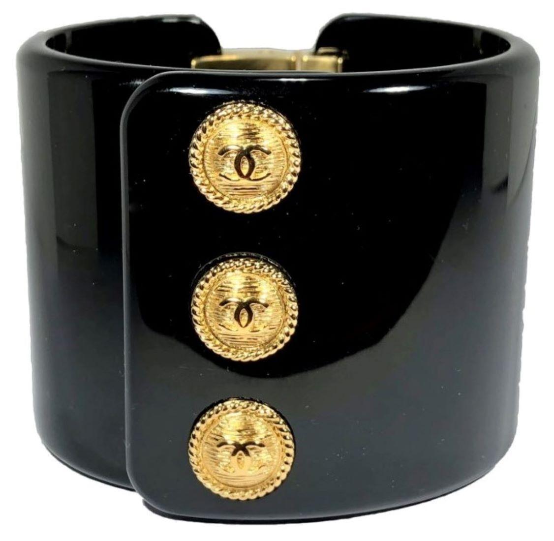 This outstanding, chic black resin Chanel cuff makes a big statement. The three gold tone buttons are highlighted with the CC logo in the center of each. Hinged on one side, Measures  just over 2 inches high. Fits a small wrist size. From the 2018