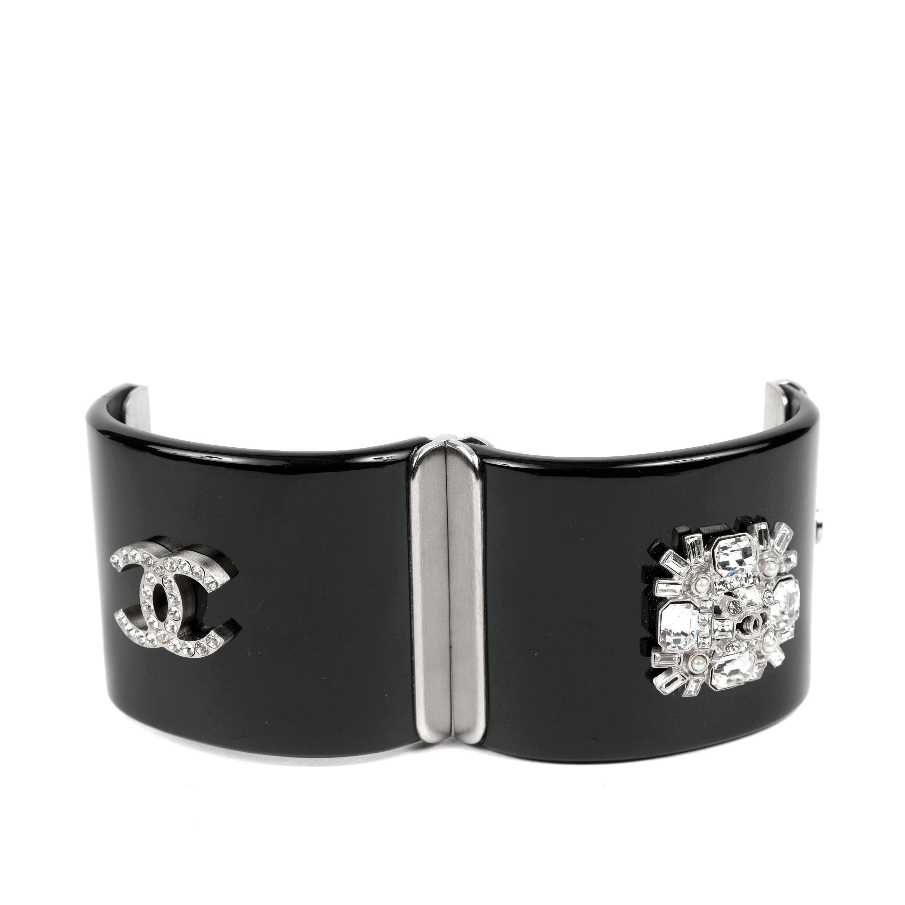 This authentic. Chanel Black Resin Crystal Verre Crest Cuff is pristine.  Wide black resin hinged cuff with crystal CC and crest. Silver hardware clasp.  Pouch or box included. 

PBF 13952
