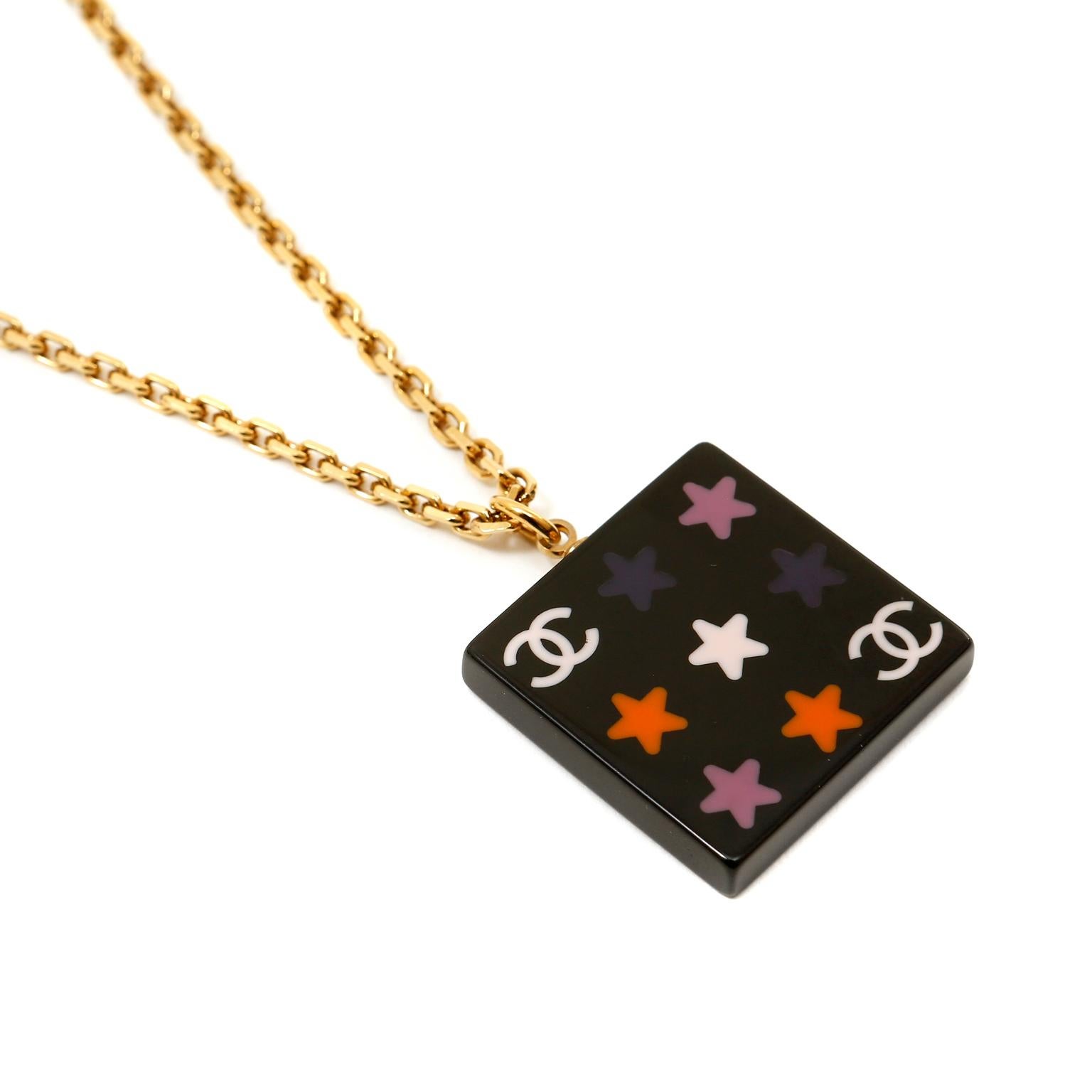 This authentic Chanel Black Resin Medallion Necklace is in excellent condition from the 2003 collection.  Black square resin medallion is covered in multicolor stars and interlocking CC emblems.  Suspended from an 18 karat gold plated linked chain,