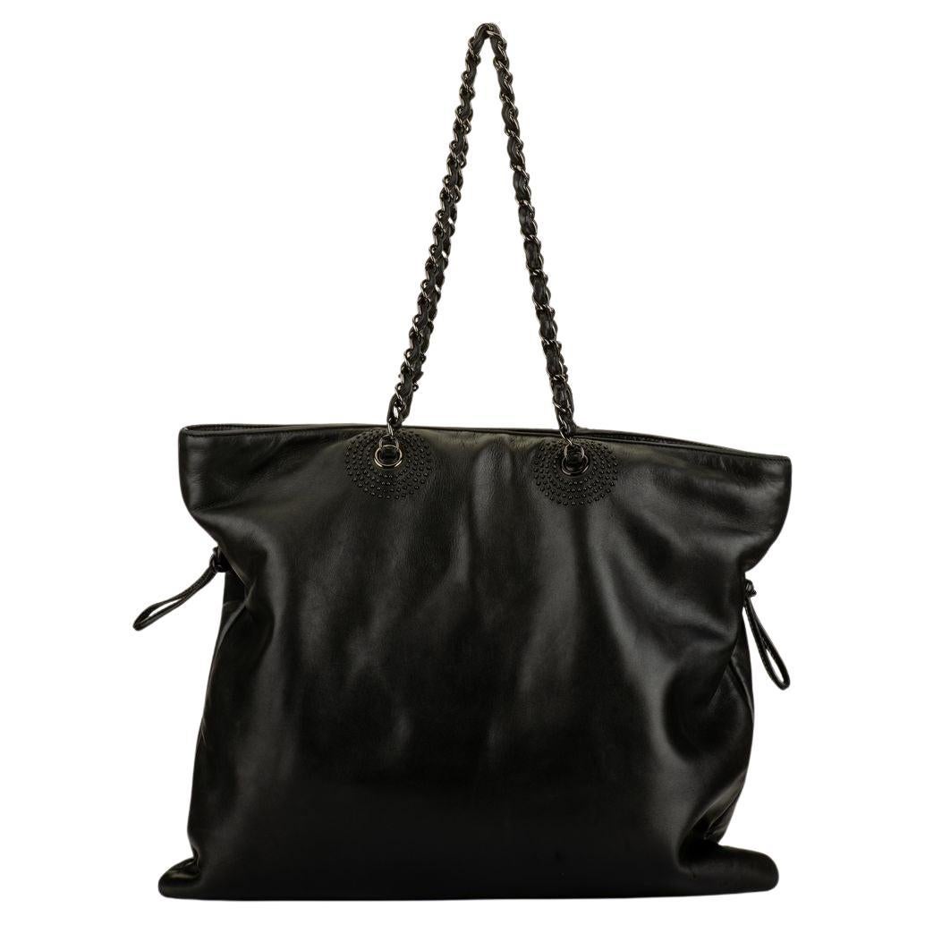 The Chanel Leather Chain Tote from the Collection by Karl Lagerfeld. Features black calfskin with embellished CC logo on front, silver toned hardware, chain link shoulder straps, snap closure and three interior pockets. Collection 12. Comes with
