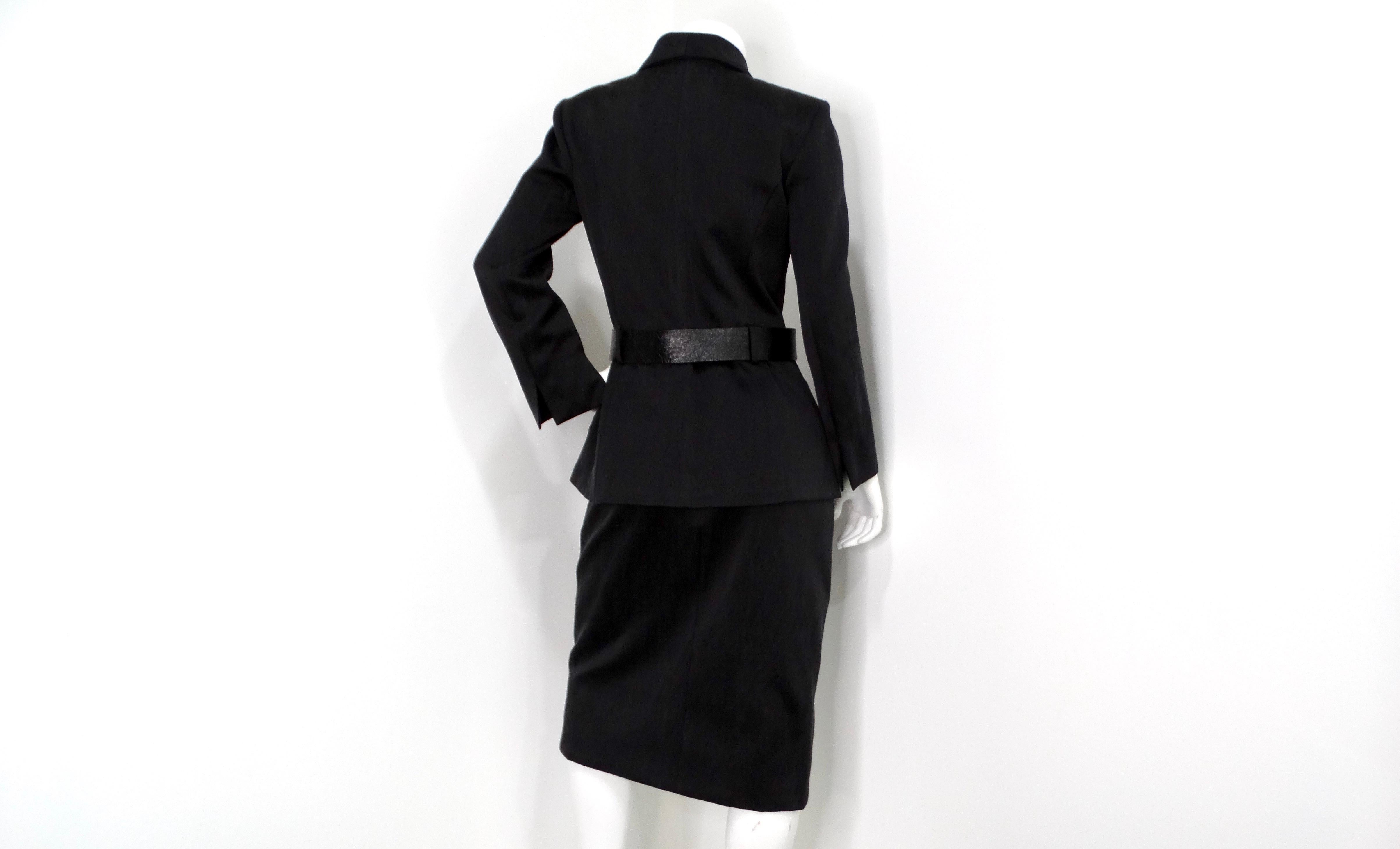 The Chanel Black Ruched & Belted Silk Jacket & Skirt Suit Set from circa 2019 epitomizes timeless elegance with modern sophistication. The jacket features a luxurious black silk fabric with subtle ruching at the bottom, creating a flattering