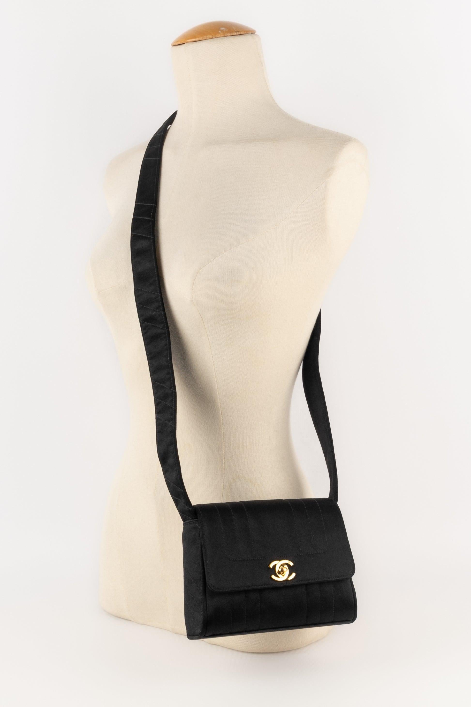 Chanel - (Made in France) Black satin A-line handbag partially topstitched. Golden metal elements and golden leather interior. Piece with a serial number. A 1994/1996 Collection, under the direction of Karl Lagerfeld.

Additional