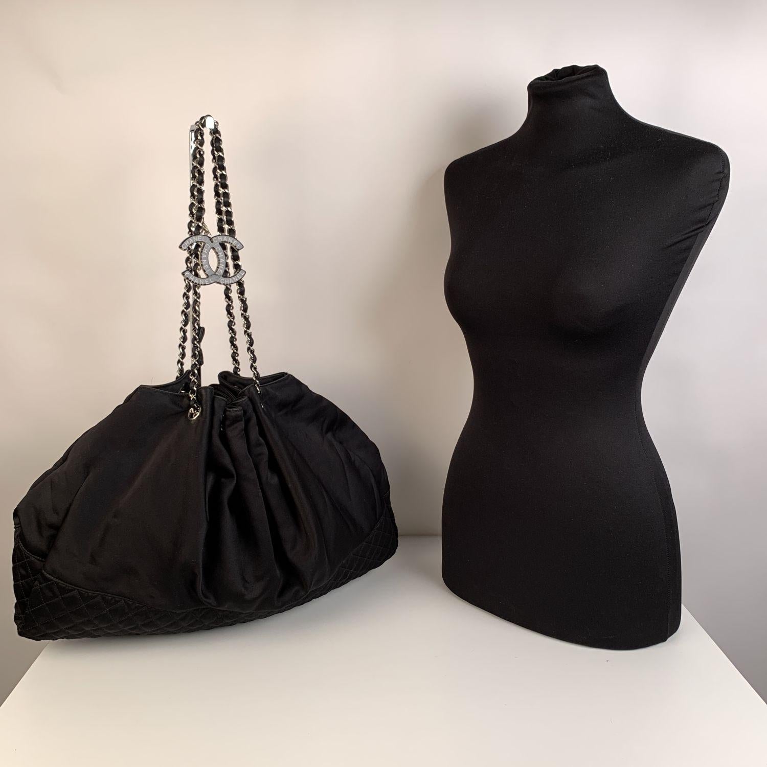 Black satin Chanel 'Melrose Cabas' Tote with diamond quilting around the base. Silver-tone hardware. Double shoulder straps with with silver-tone chain link with interwoven satin. The Bag is very spacious and it features a cinched top, a big resin