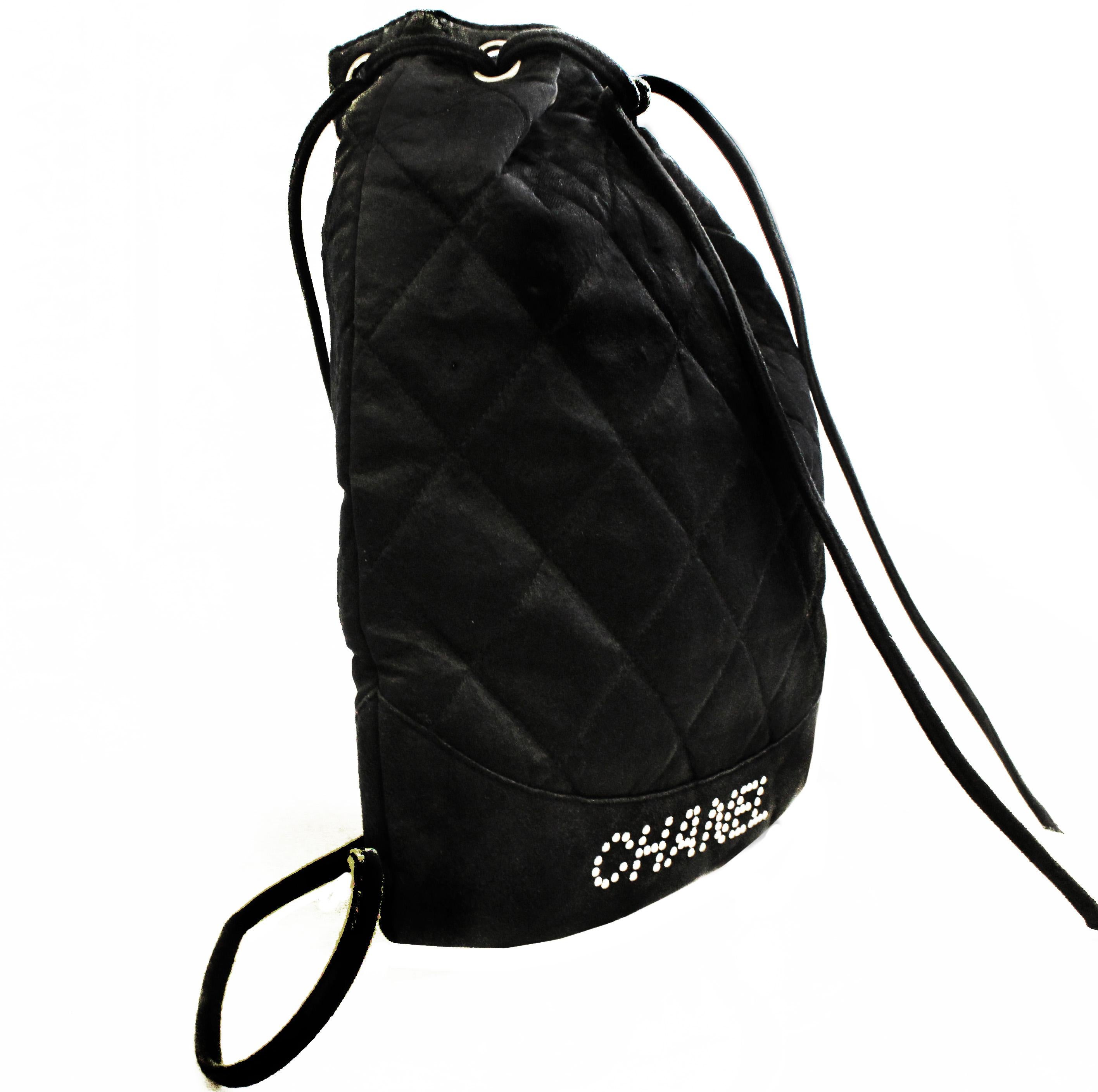 This rarely found Chanel black satin drawstring mini backpack incorporates a black suede leather band at the bottom for extra support. On the suede band the Chanel name is accentuated with mini faux pearls.  It's light weight and very feminine