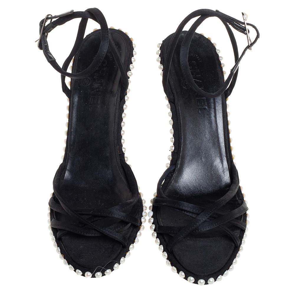 Diese Sandalen von Chanel spiegeln die makellose Schuhmacherkunst des Labels wider. Die aus schwarzem Satin gefertigten Schuhe haben einen zeitlosen Reiz und sind mit Riemen versehen. Sie sind mit sorgfältig platzierten Perlen verziert, die ihnen