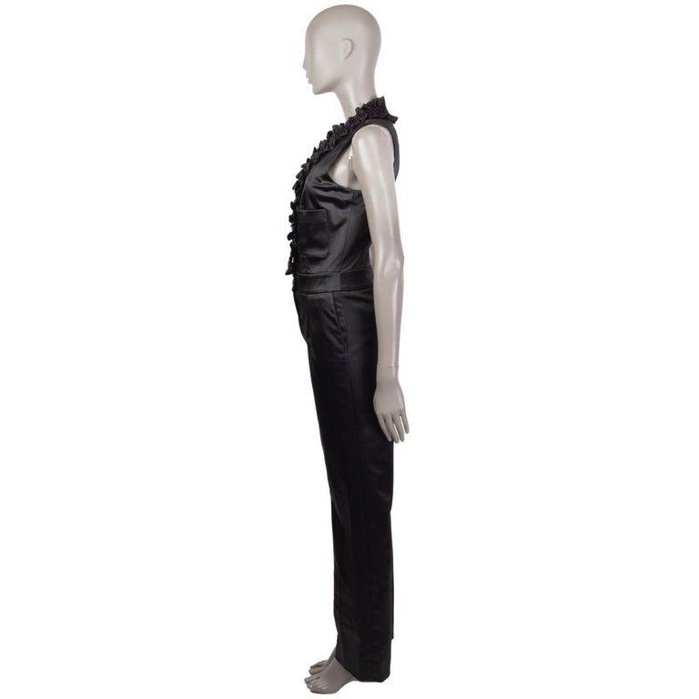 Chanel satin jumpsuit in black acetate (48%), nylon (45%), and spandex (7%). With smocked ruffled on the front, two patch pockets on the chest, two slit pockets on the sides, and two welt pockets on the back. Closes with concealed buttons, one
