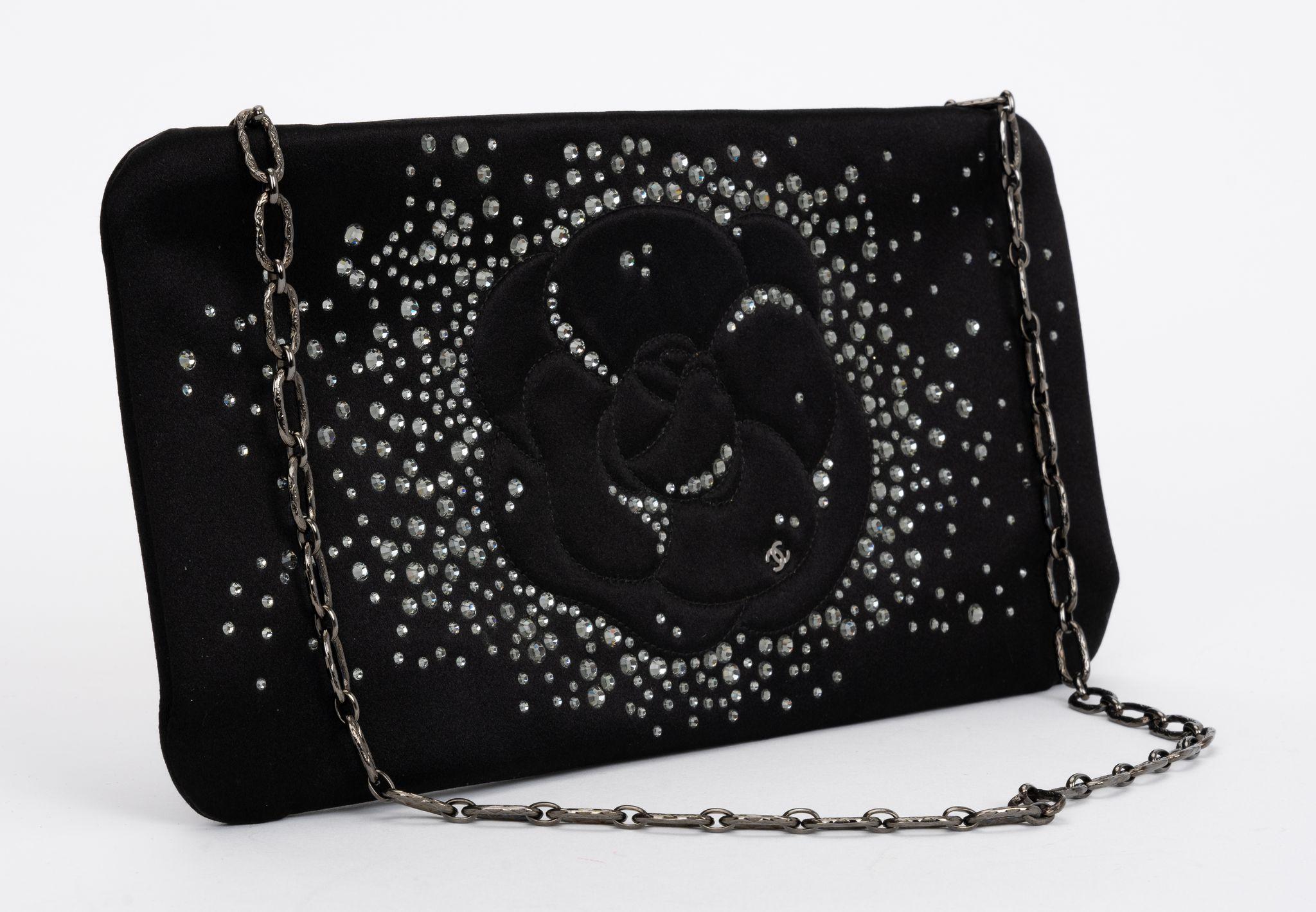 Pochette noire Chanel de la Collection Printemps/Été 2010 
de Karl Lagerfeld. Comprend des accessoires de couleur argentée et une bandoulière à maillons de chaîne.
et des ornements en cristal. Doublure en satin et poche intérieure