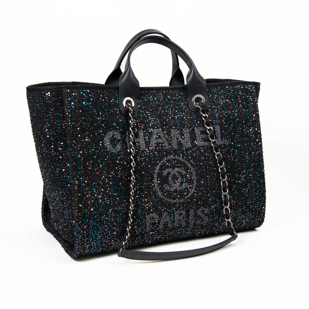 100% Authentic 

This stylish tote is crafted of sequined canvas in black, with a glittered Chanel Rue Cambon Paris logo. It features rolled leather top handles and fabric threaded silver chain shoulder straps. The top is open to a black fabric