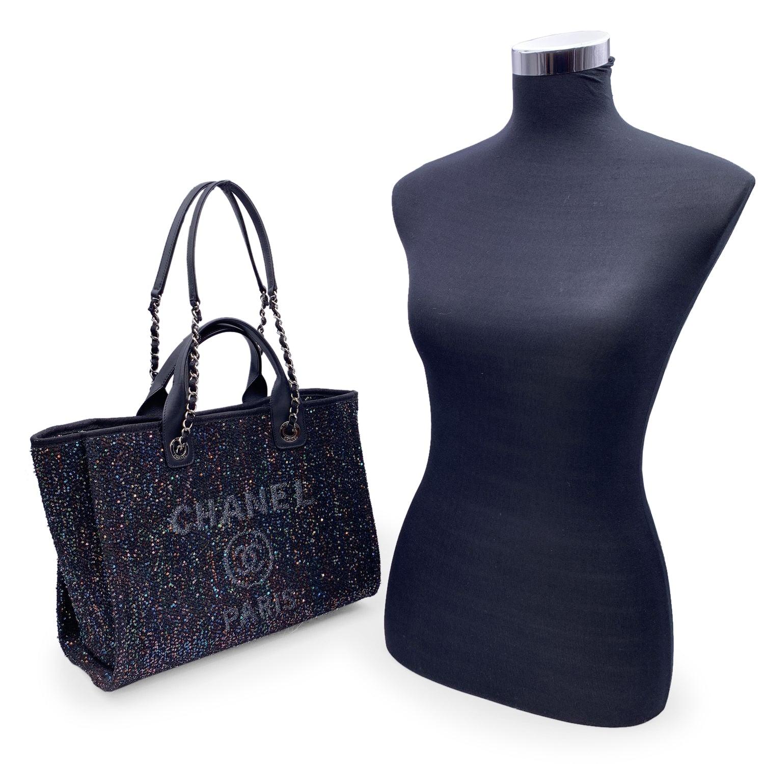 Beautiful Chanel 'Deauville' tote, crafted in black canvas with an embroidered 'Chanel CC Paris' logo and allover shimmering multicolored sequins. Period/Era: 2020. Double black leather top handles and silver metal and interwoven leather shoulder