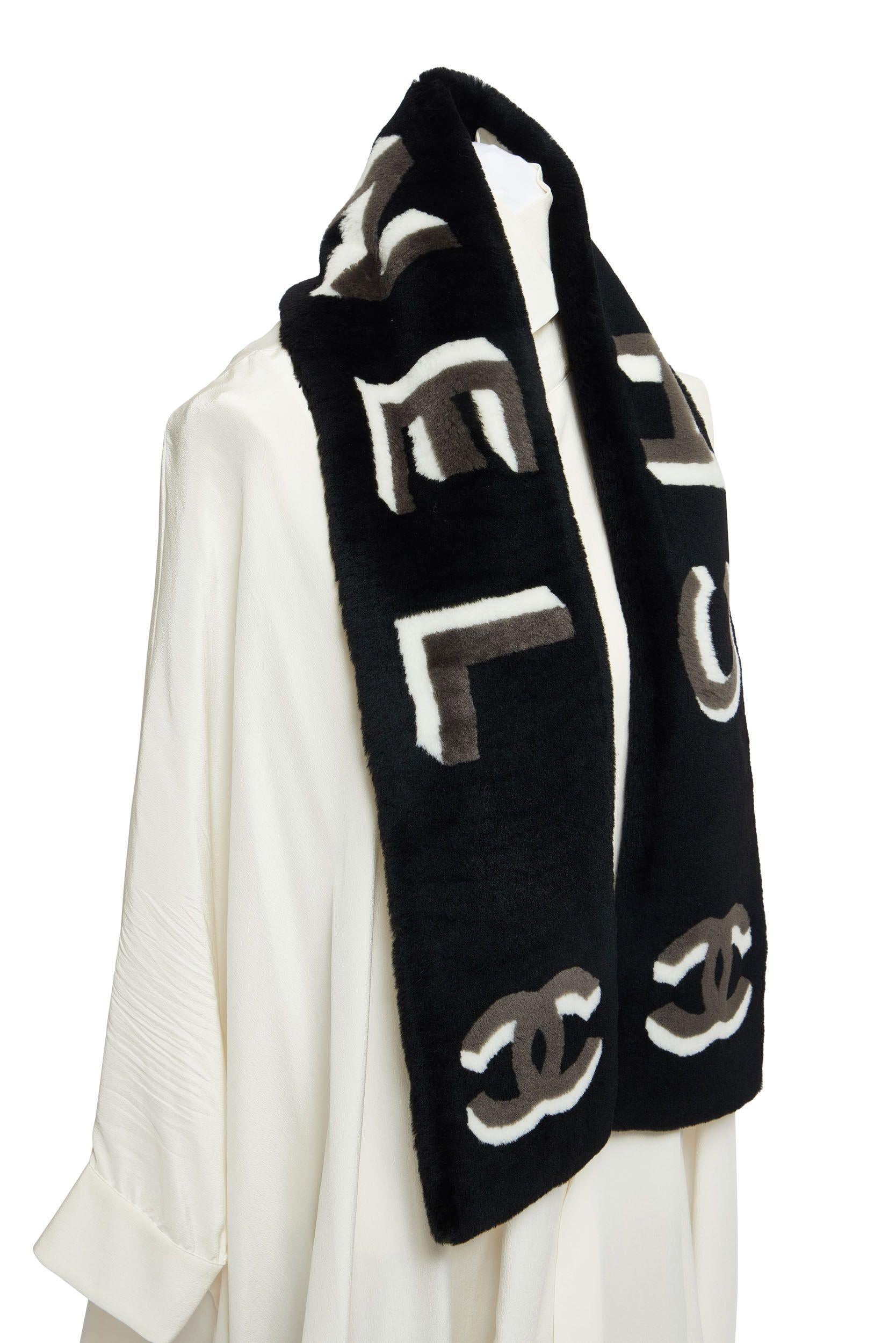 Nouvelle écharpe Chanel en peau de mouton noire avec lettres Chanel et logo CC tridimensionnels blancs et gris. Doublure chaude en cachemire noir.