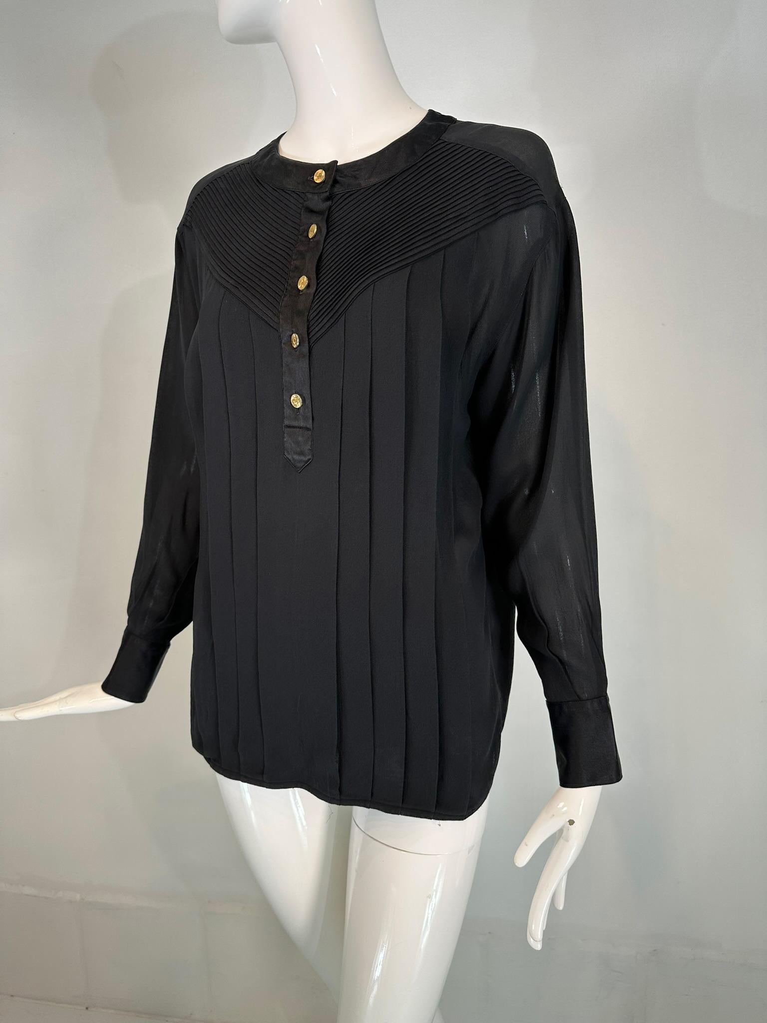 Chanel black silk chiffon & satin pleated long sleeve button front blouse. Beautiful Long sleeve sheer silk chiffon blouse with dropped shoulders, double button cuffs with gold Chanel logo buttons. The pull on blouse has a front satin button placket