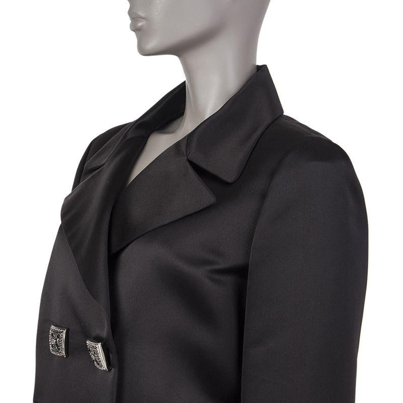 Chanel double-breasted satin blazer in black silk (100%). With notch collar, two pockets on the front sides, two-button cuffs, and signature chain around the inside of the hemline. Closes with embellished square buttons in silver metal with red and