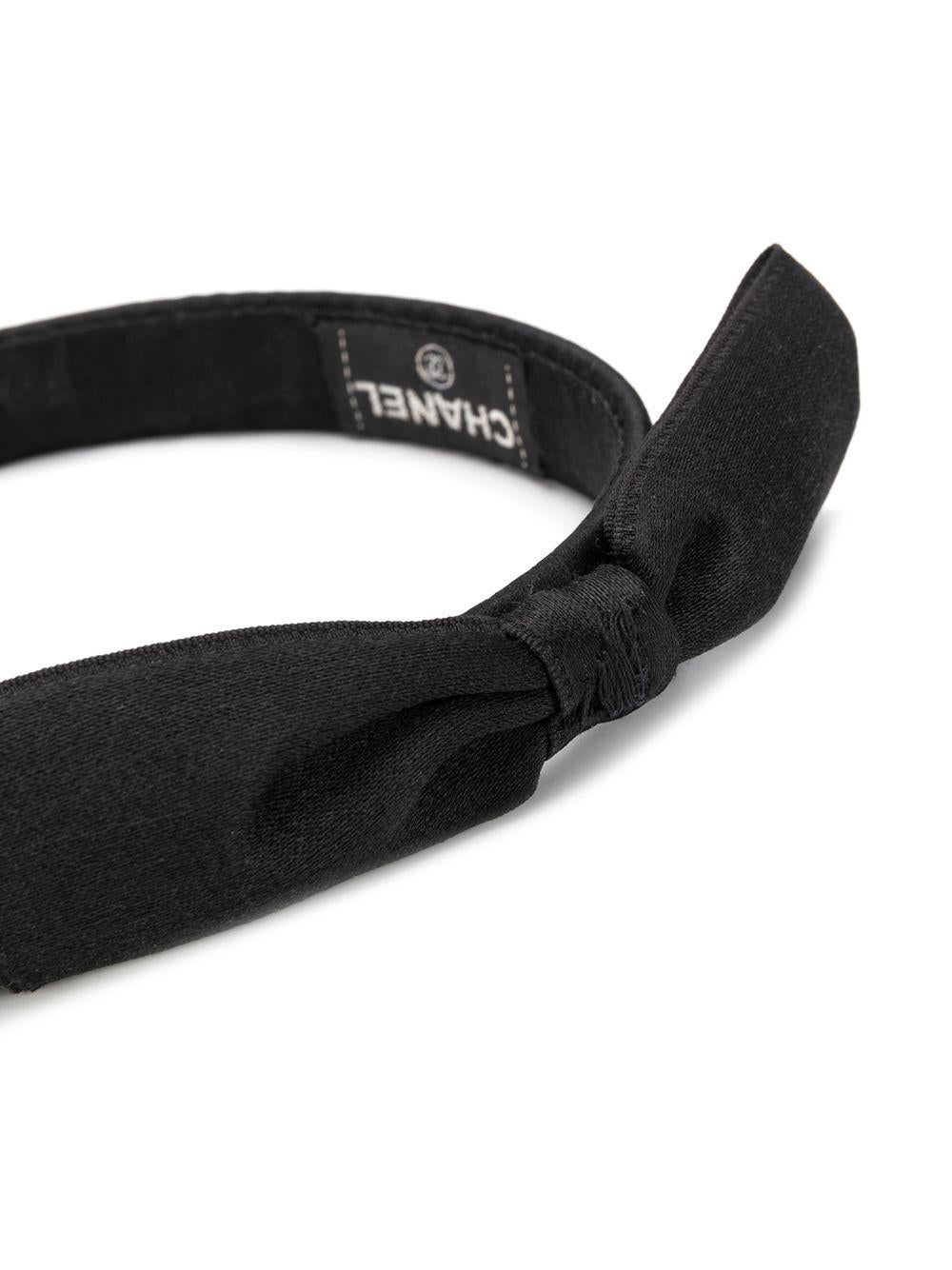 Add a youthful, preppy vibe to your look with this pre-owned black silk headband from Chanel. Crafted in France, this elegant accessory boasts a slim, round shape, an internal logo patch and a distinctive bow embellishment with frayed edges for an