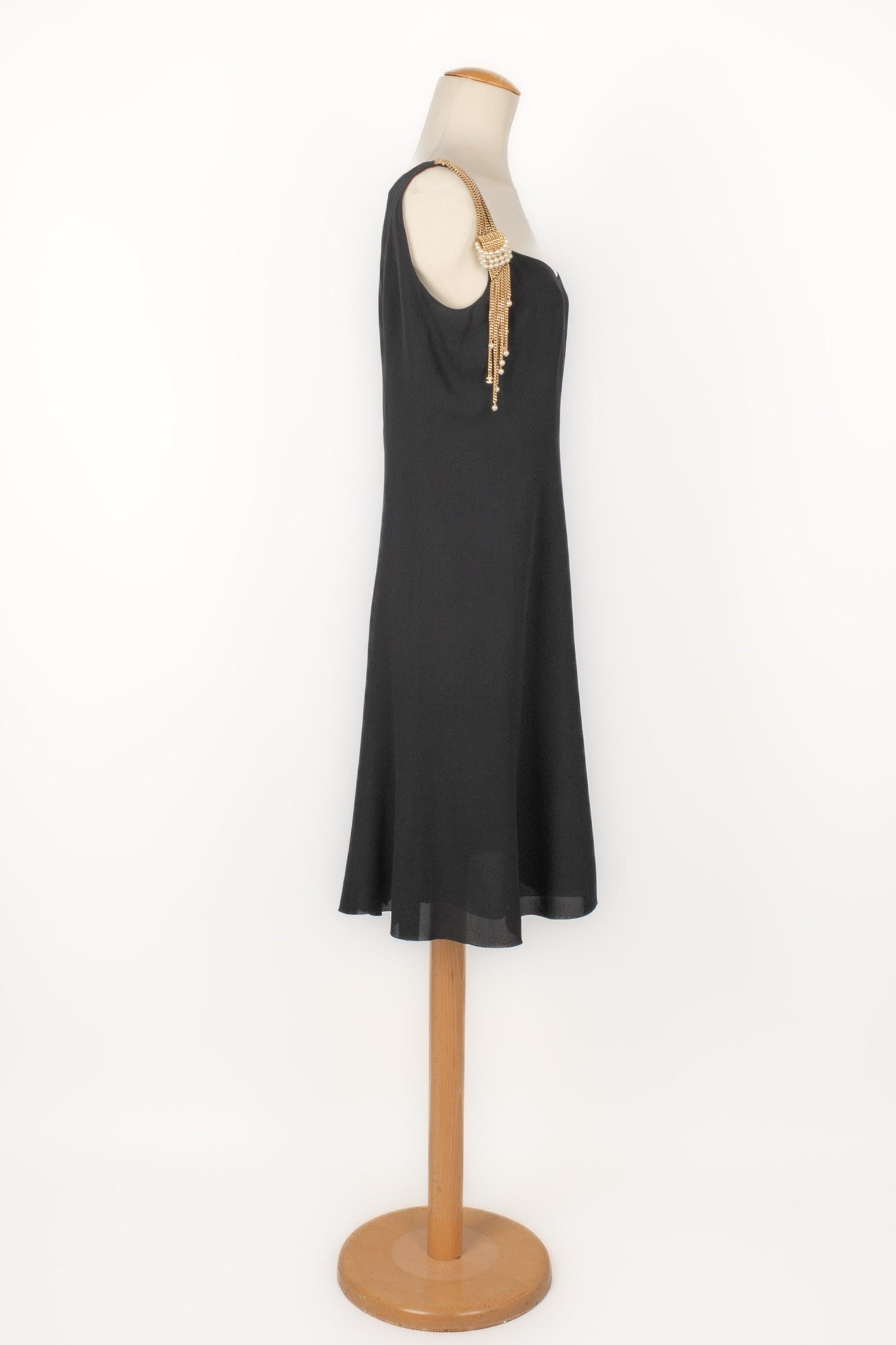 Chanel - (Fabricado en Francia) Vestido de seda negra de largo medio, tirantes adornados con cadenas de metal dorado y perlas de fantasía. Talla 40FR indicada. Colección Crucero 2001, bajo la dirección de Karl Lagerfeld.

Más información:
Estado: