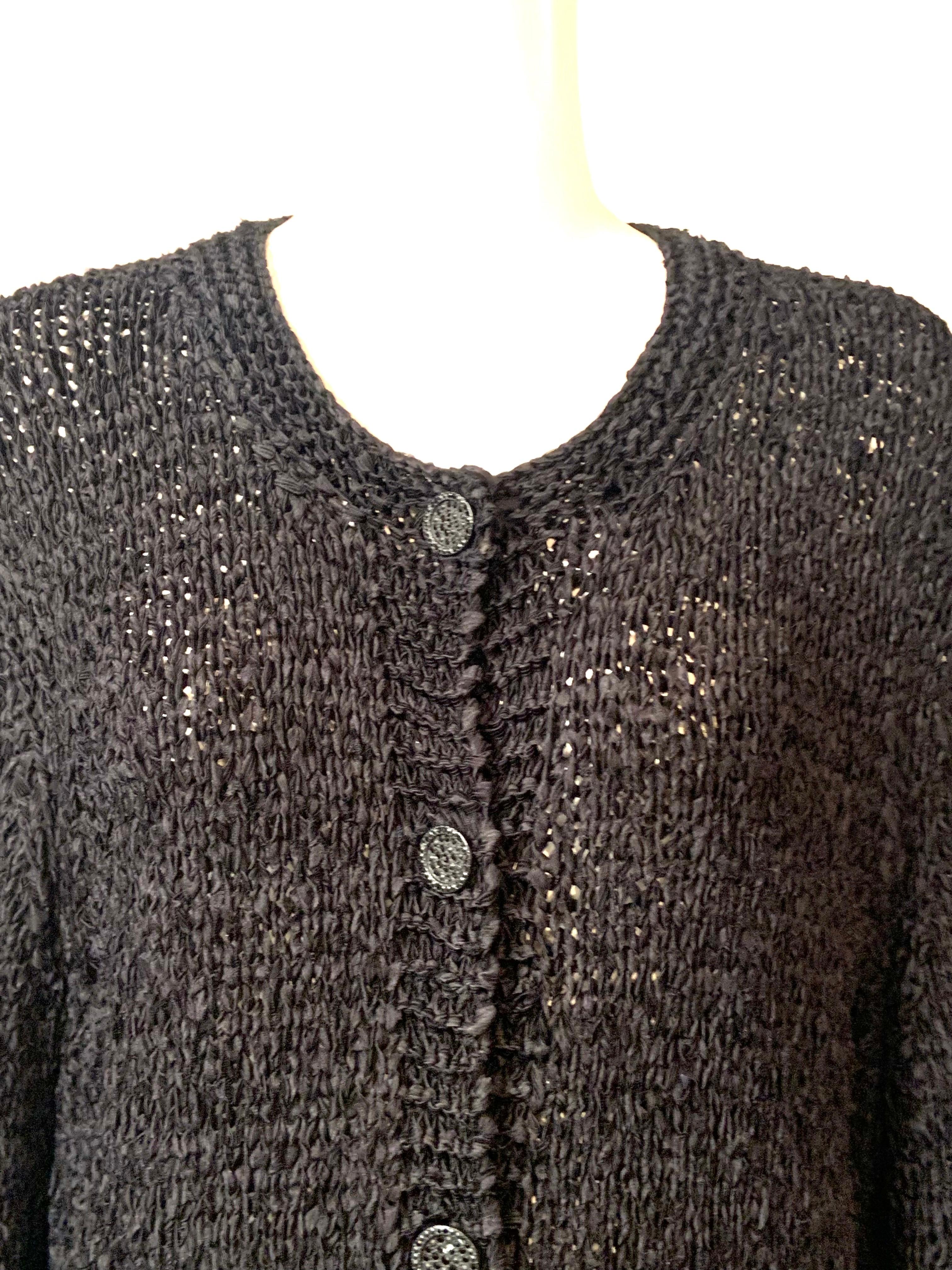 Diese schöne schwarze Chanel Strickjacke mit Seidenbändern ist fast das ganze Jahr über tragbar.  Er ist leicht genug für einen Sommerabend und kann mit einer weiteren Schicht für die kühleren Monate kombiniert werden. Der Körper des Pullovers wird