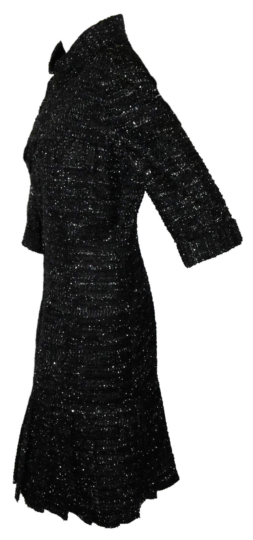 Chanel black and silver tone lurex threads all over the dress giving it a tweed effect. This  mid length dress contains a high funnel collar and for closure a long front zipper.  This dress includes 3/4 sleeves with lapel at each end of sleeve and