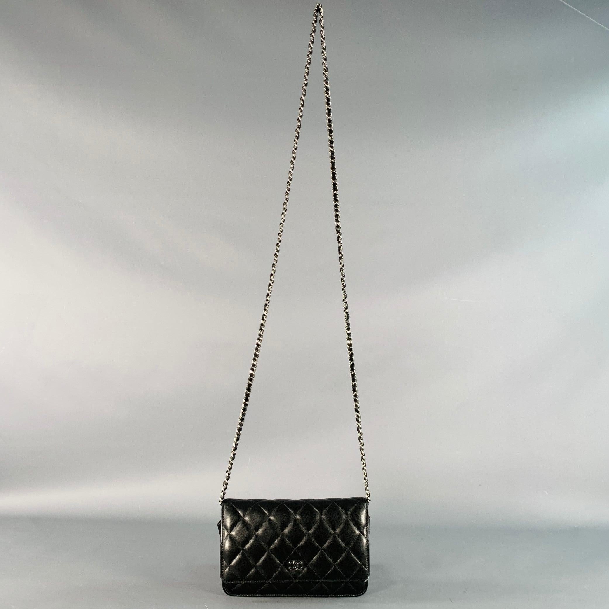 CHANEL Handtasche
aus schwarzem Leder mit einem Portemonnaie im Stil einer Brieftasche mit mehreren Kartenfächern im Inneren, einem charakteristischen Steppmuster, einem Schulterriemen aus gewebtem Leder und silberfarbenen Metallkettengliedern sowie
