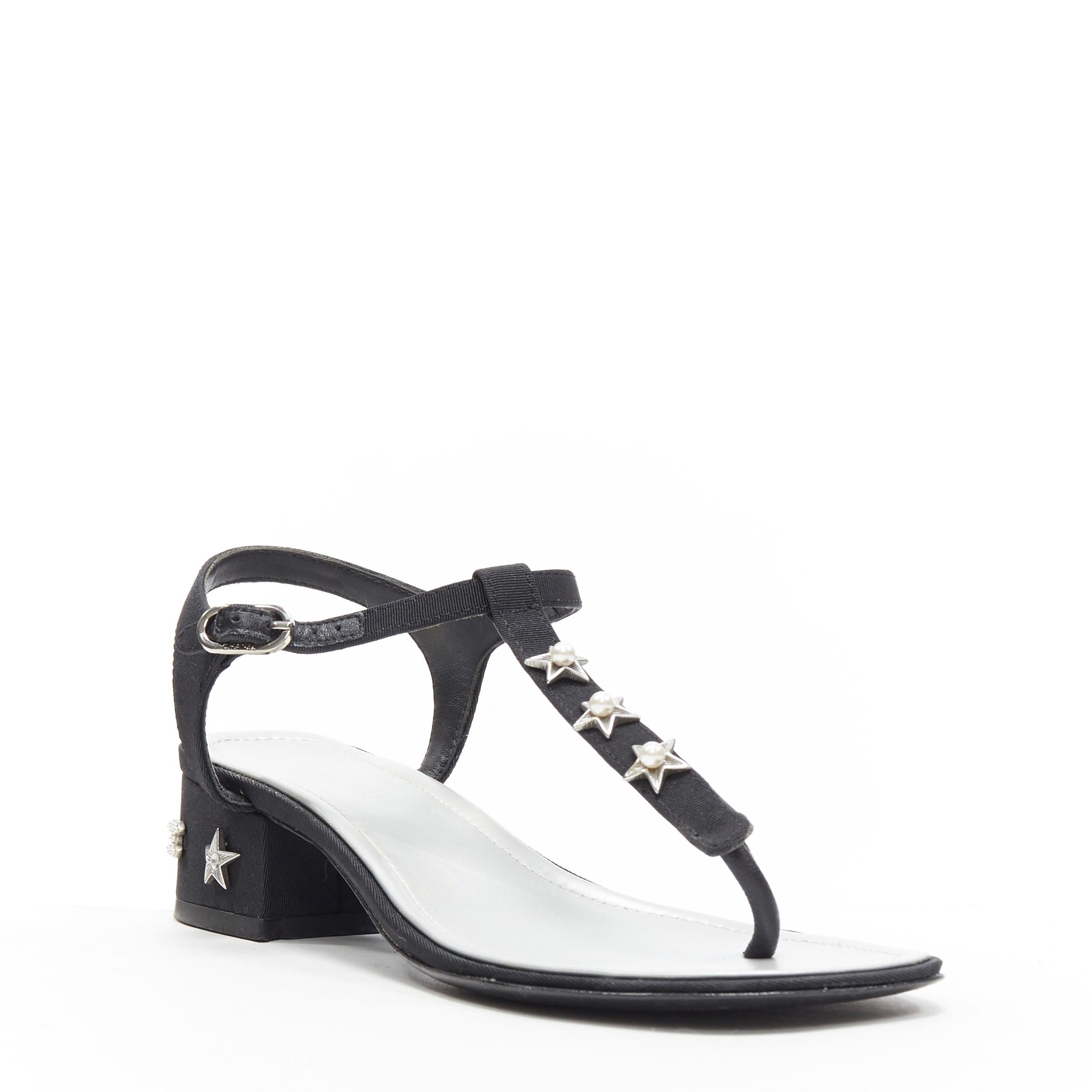 CHANEL black silver star pearl CC studded block heel T-strap thong sandals EU39
Brand: Chanel
Model Name / Style: Thong sandals
Material: Fabric
Color: Black
Pattern: Solid
Closure: Ankle strap
Extra Detail: High (3-3.9 in) heel height. Open toe.