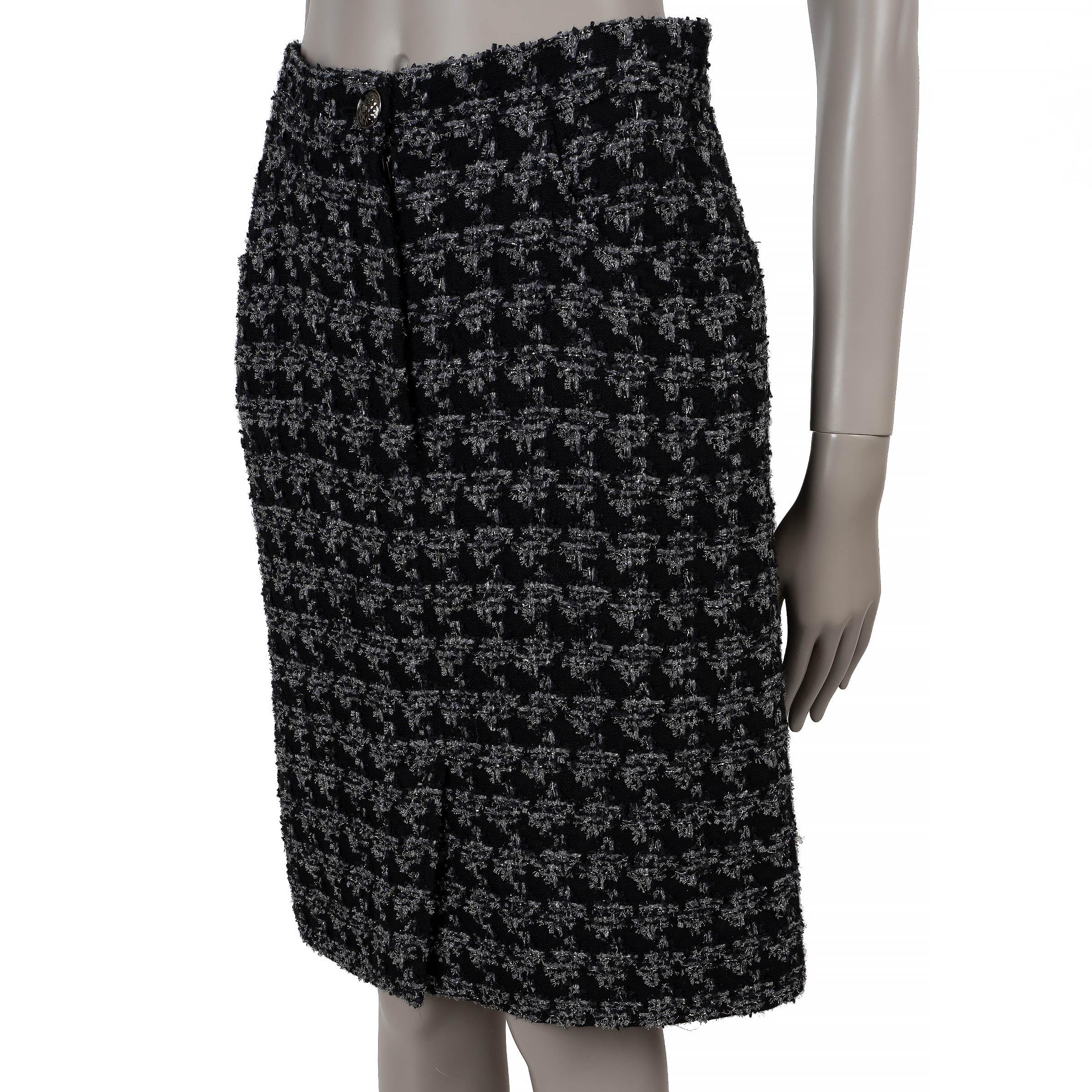 Cette jupe en tweed pied-de-poule au genou, 100% authentique Chanel, en laine (40%), soie (24%), nylon (13%), polyester (13%), acrylique (10%), est un classique raffiné avec une touche de modernité. Doté de poches avant, d'une fente sur le devant et