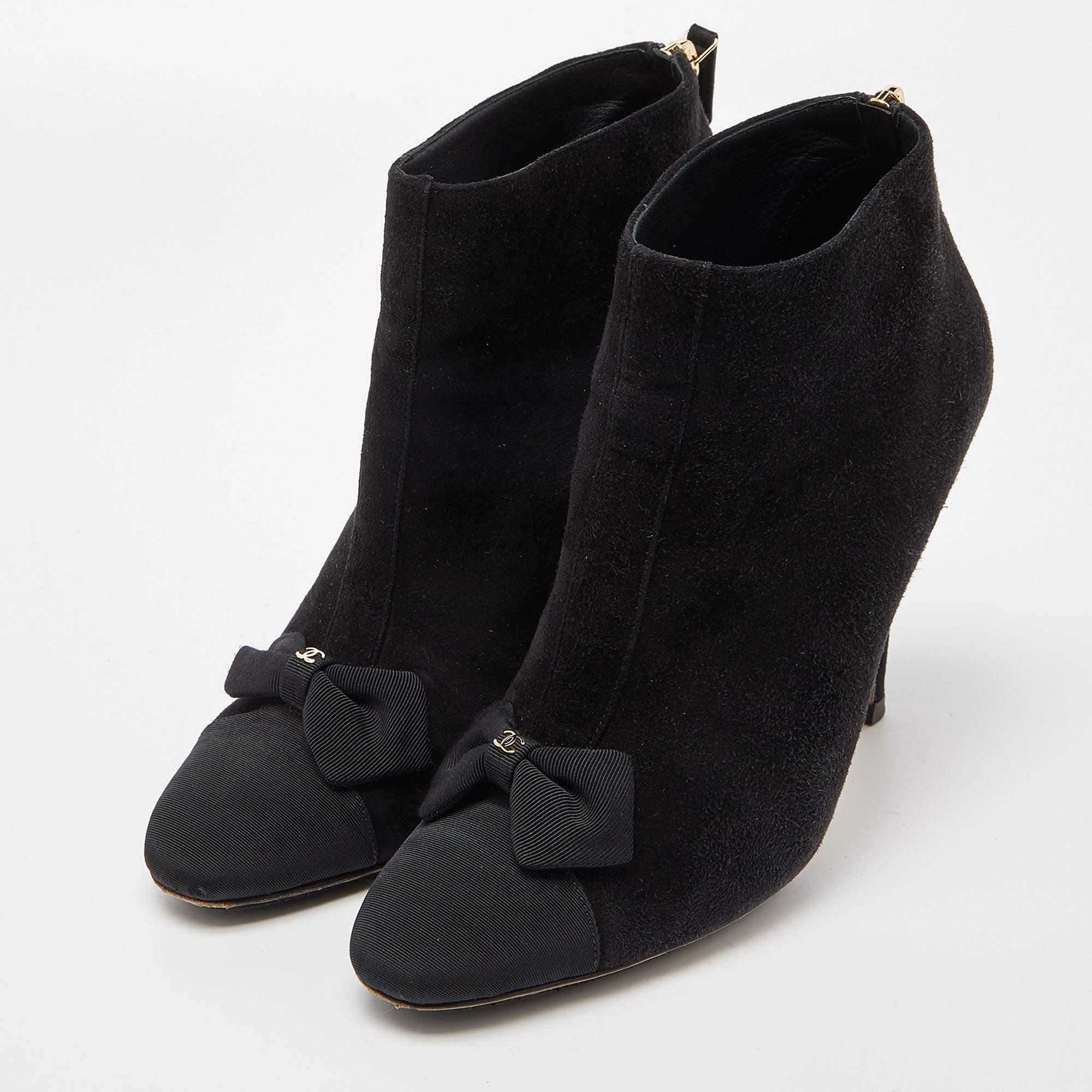 Let your latest shoe addition be this fabulous pair of ankle boots from Chanel. The black boots are crafted from suede and feature canvas cap toes, 11 cm heels, and bow details.