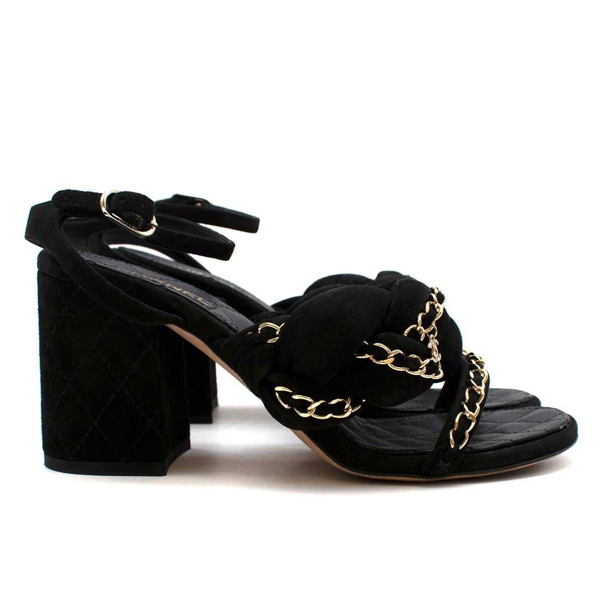 Chanel Black Suede & Chain Heeled Sandals 

- Made of super soft suede 
- Neutral black hue 
- Legendary CC logo pendant 
- Chain details to the straps 
- Braided detail 
- Round toes 
- Gold-tone hardware 
- Signature quilting texture to the heel
