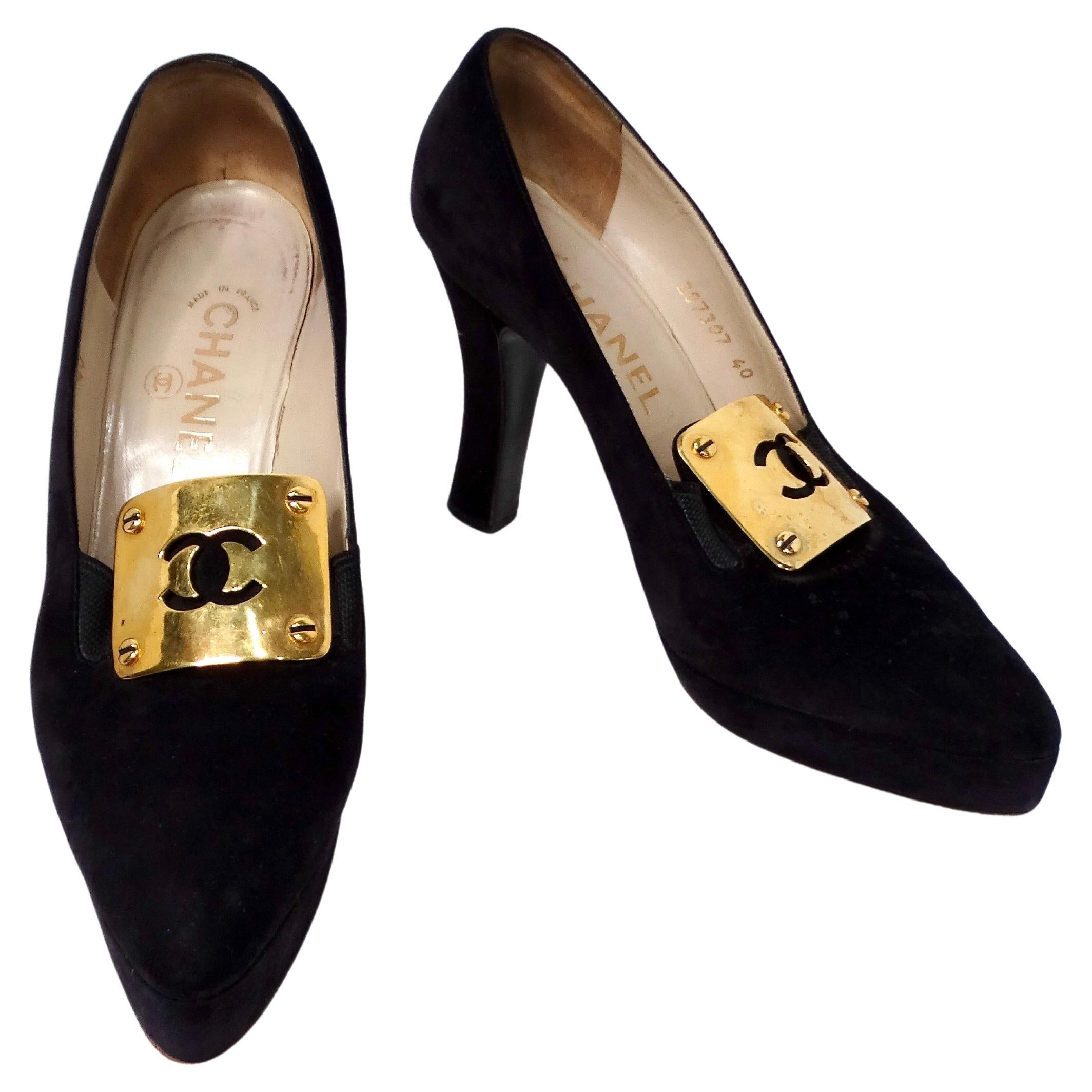 Les talons mocassins Chanel en daim noir avec plaque à logo CC, datant des années 1980-90, incarnent l'élégance intemporelle et la sophistication de l'artisanat. Confectionnés en daim noir, ces mocassins arborent le logo CC emblématique en métal