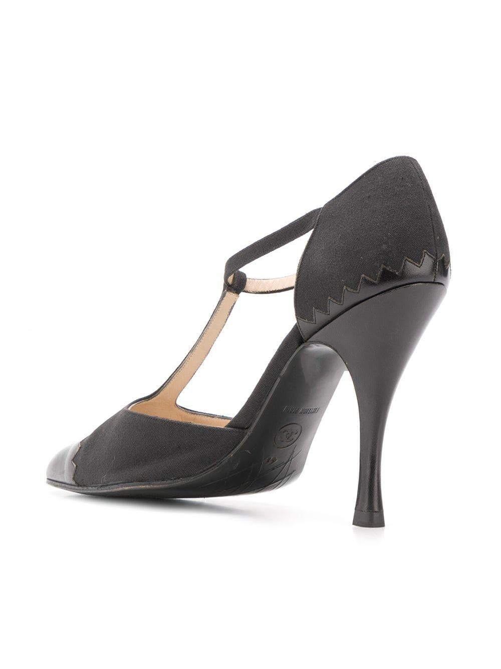 Crafted from a combination of black calf leather and canvas, these vintage pumps by Chanel are for the fashion forward, featuring a 10cm stiletto heel and branded insole, a pointed toe with a T-strap accentuating the front, and an ankle strap