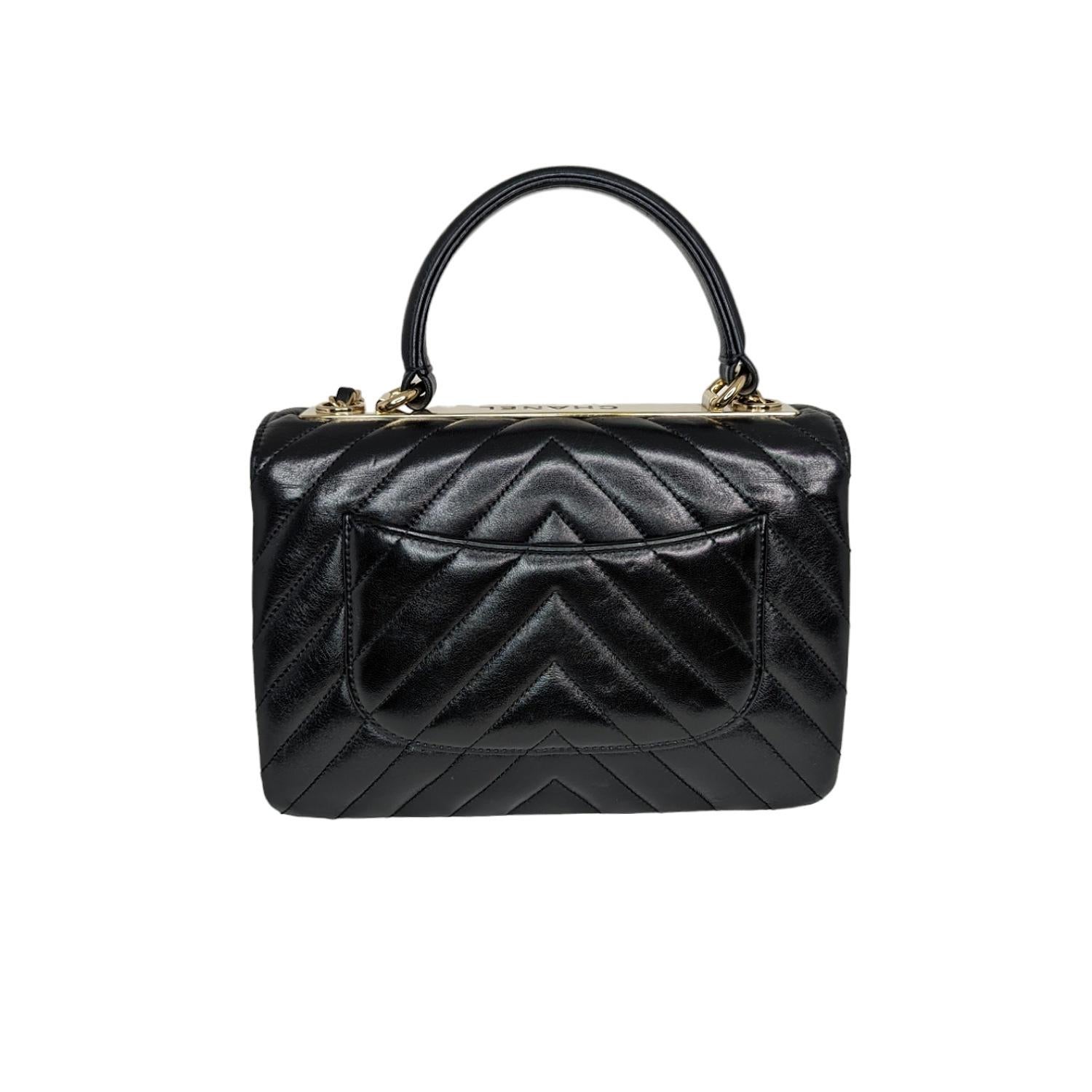 Diese stilvolle Handtasche ist aus schwarzem Lammleder mit Chevron-Steppung gefertigt. Der ikonische CC-Drehverschluss mit goldfarbener Hardware auf der Vorderseite. Auf der Rückseite der Tasche befindet sich ein praktisches Steckfach, und der