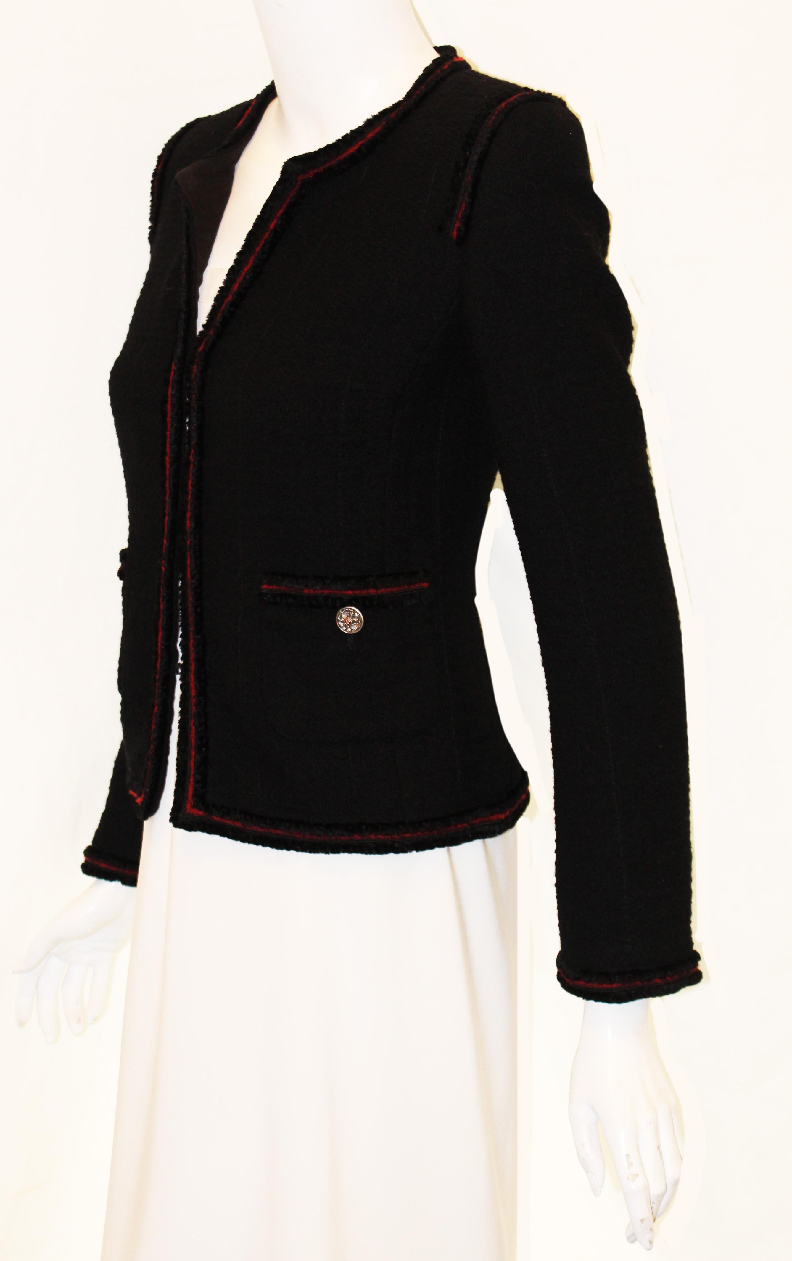 Chanel black tweed jacket is trimmed with red wool yarn and black velvet around neckline, down the front, around the hem, on on shoulders, cuffs and top of patch pockets.   This fall 2009 Paris to Moscow collection incorporates a more military look