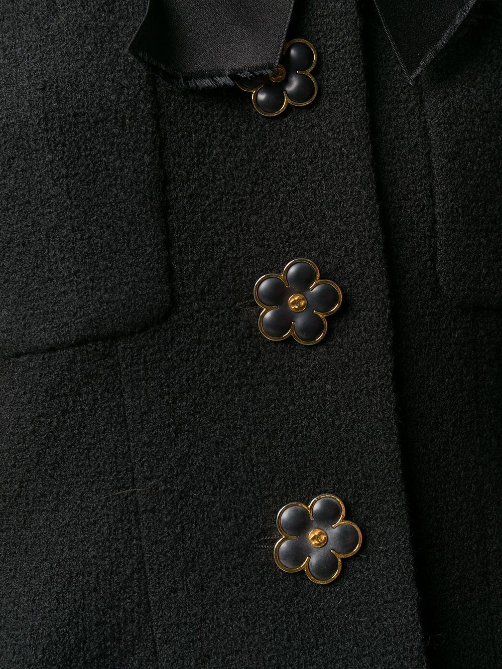 Expertly cut and crafted in France from pure black wool, this pre-owned, long-sleeved jacket from Chanel showcases long sleeved design, with a pointed collar and a distinctive front bow fastening. The front button fastening is embellished with the