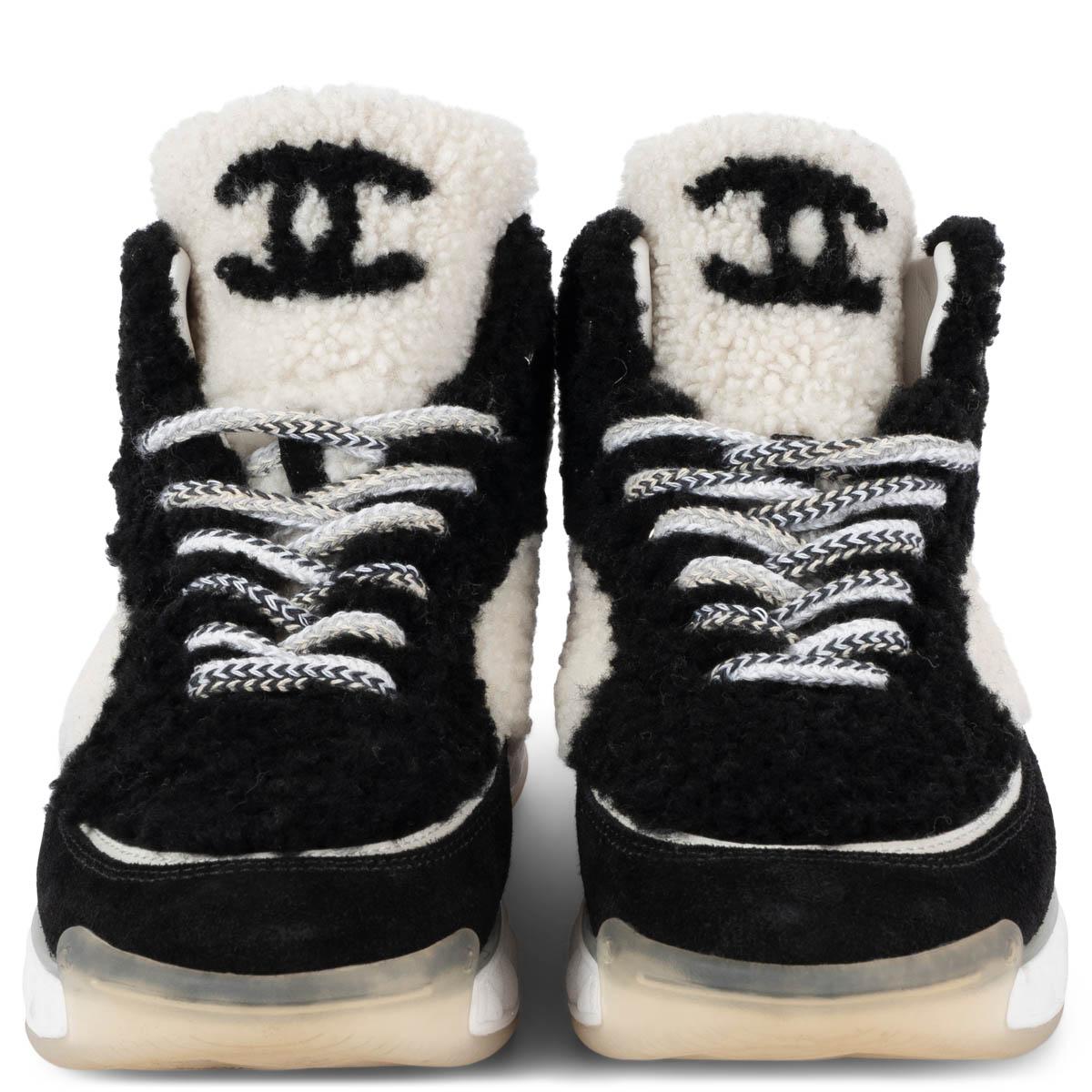 100% authentic Chanel lace-up high-top sneakers in black & white shearling and a black suede leather tip. The design features a chunky grey, white and clear rubber sole. Have been worn and show some very soft discoloration on the sole. Overall in