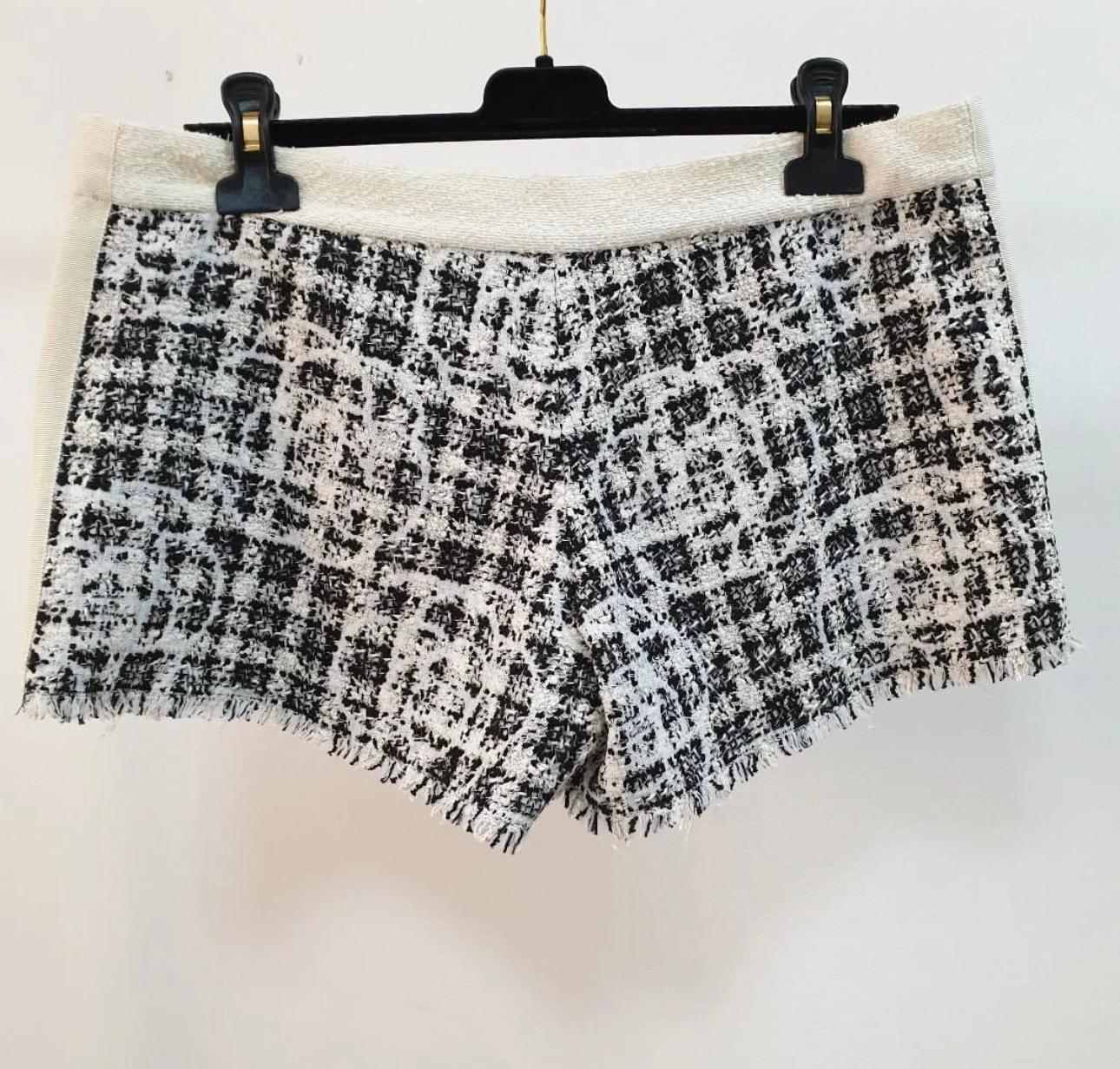 Crafted in a monochrome tweed and designed with a camellia pattern throughout and faux pearl button details at front with 'CC' logo. 
Features an elasticated back, slip on style. 
Sz.38
Very good condition.
Hanger is not included.