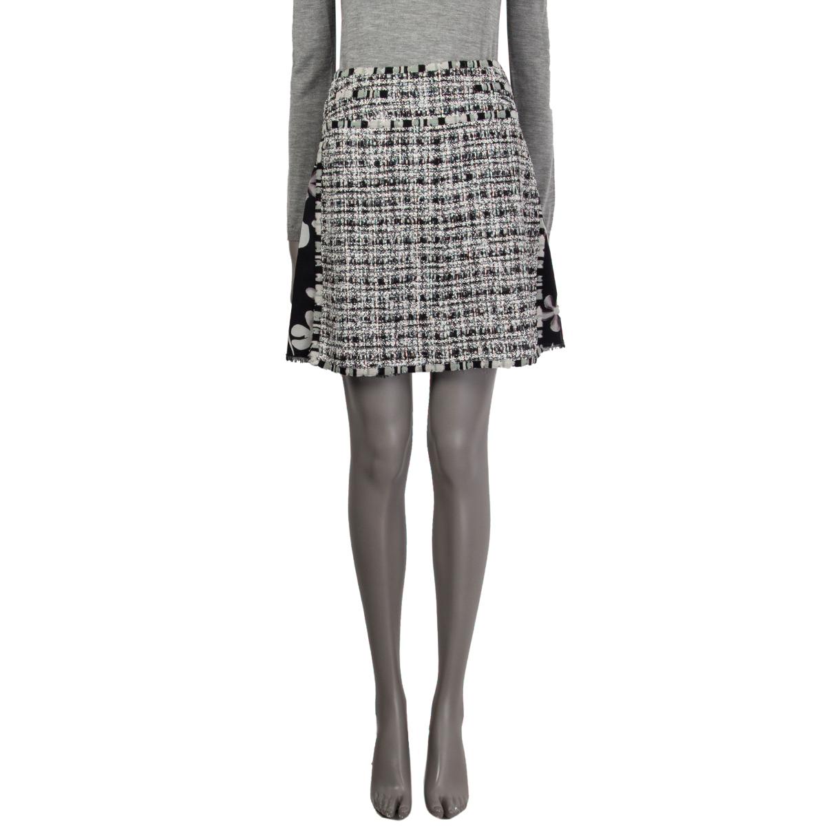100% authentic Chanel plaid-tweed and floral A-line layered skirt in black and off-white rayon (40%), cotton (20%), silk (20%), nylon (10%), and wool (10%). With striped cotton trims, high slits on the sides, and fray hemline. Closes with hook and